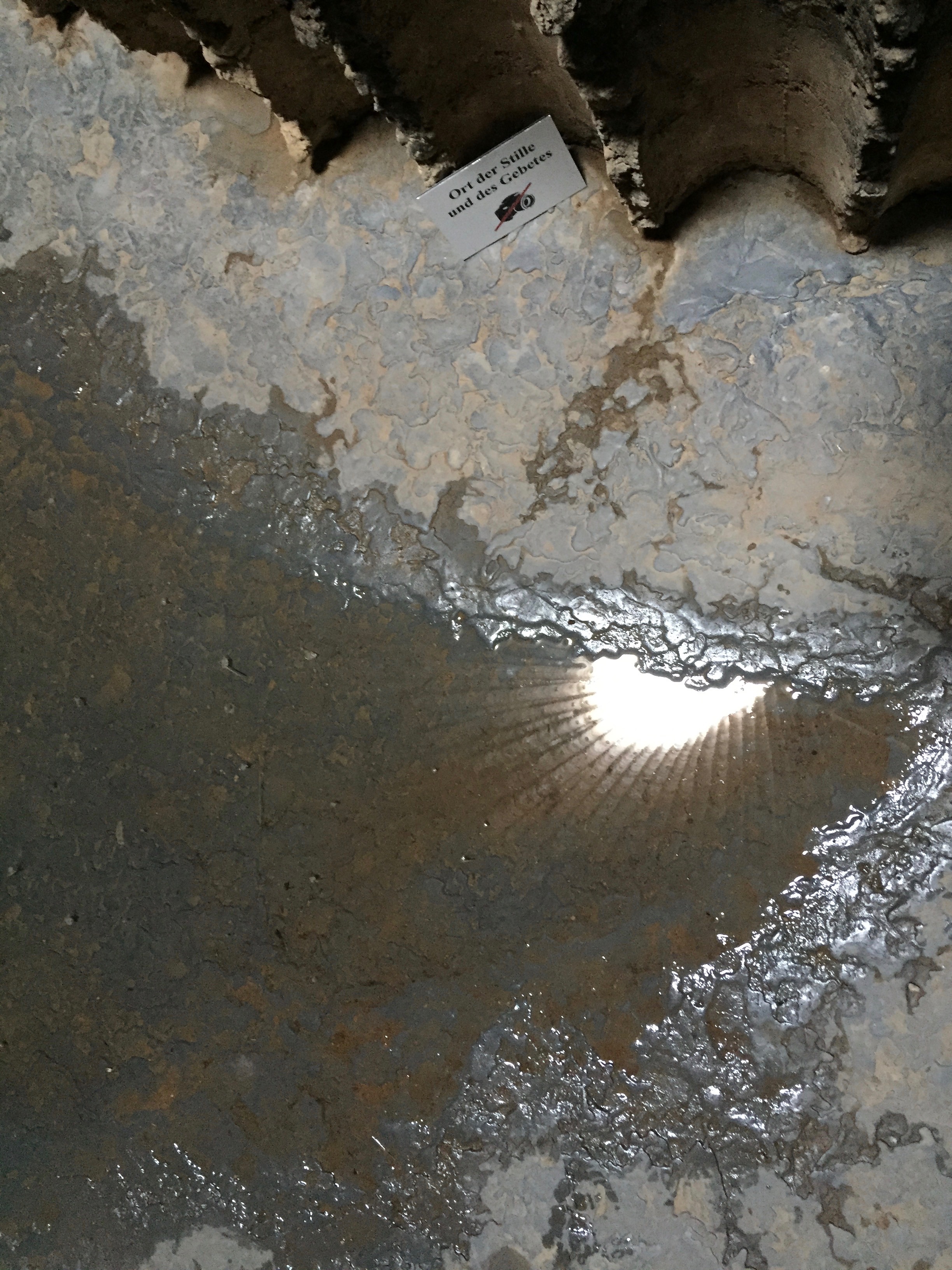 Auf der Zinnbleischicht am Boden der Feldkapelle Bruder Klaus steht das  Regenwasser. Mit der Spiegelung der zentralen Öffnung verschmelzen Wasser, Licht und Material zu einem veränderlichen Bild.