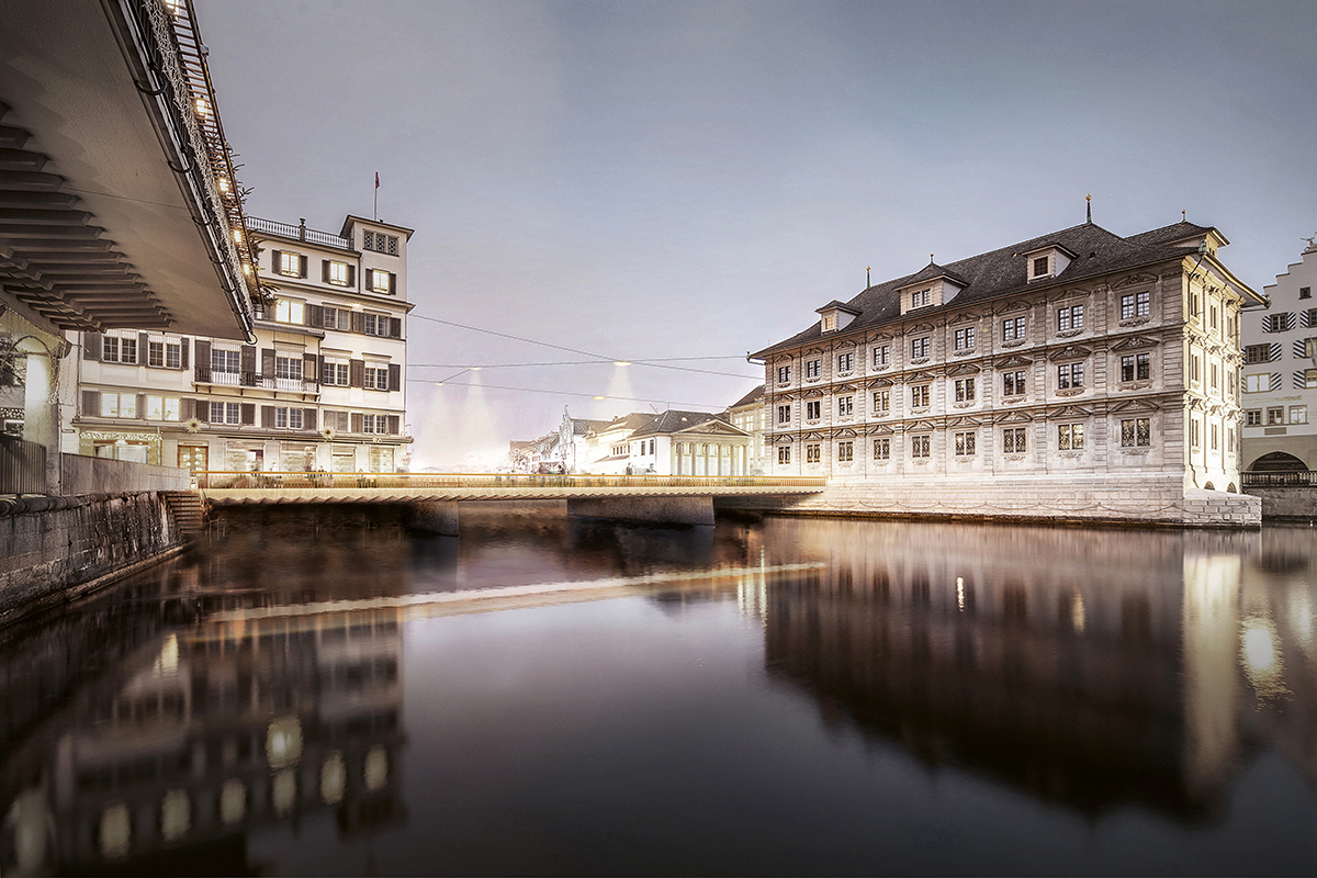 Ansicht flussaufwärts: Mit den zurückversetzten Pfeilern erscheint die Brücke als leichtes Band über der Limmat.  Seilleuchten belichten den Ort.