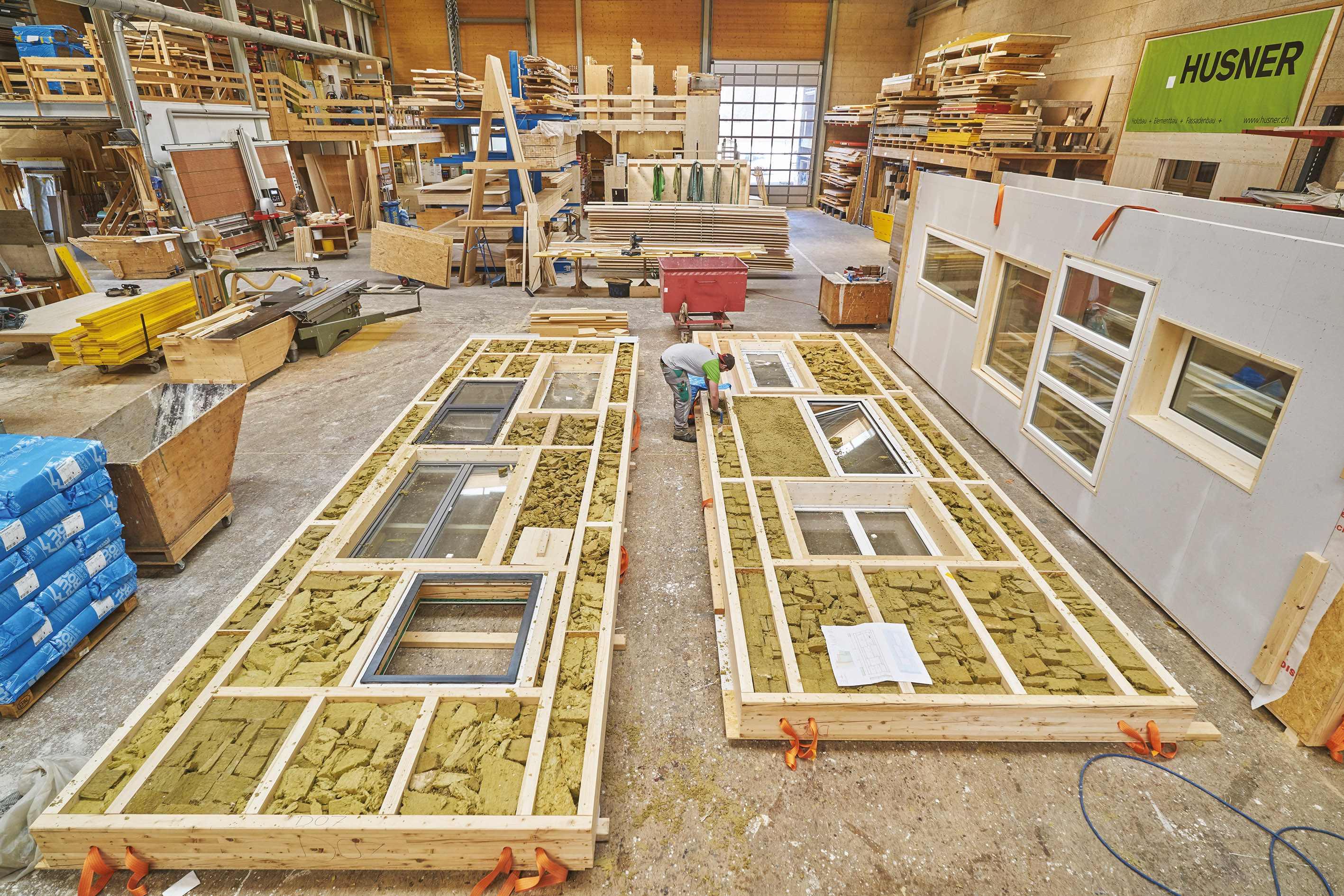 Les modules des nouvelles façades en cours de montage en atelier : des cadres en bois intègrent des fenêtres de différentes tailles et l’isolation. Tous ces matériaux ont été récupérés.