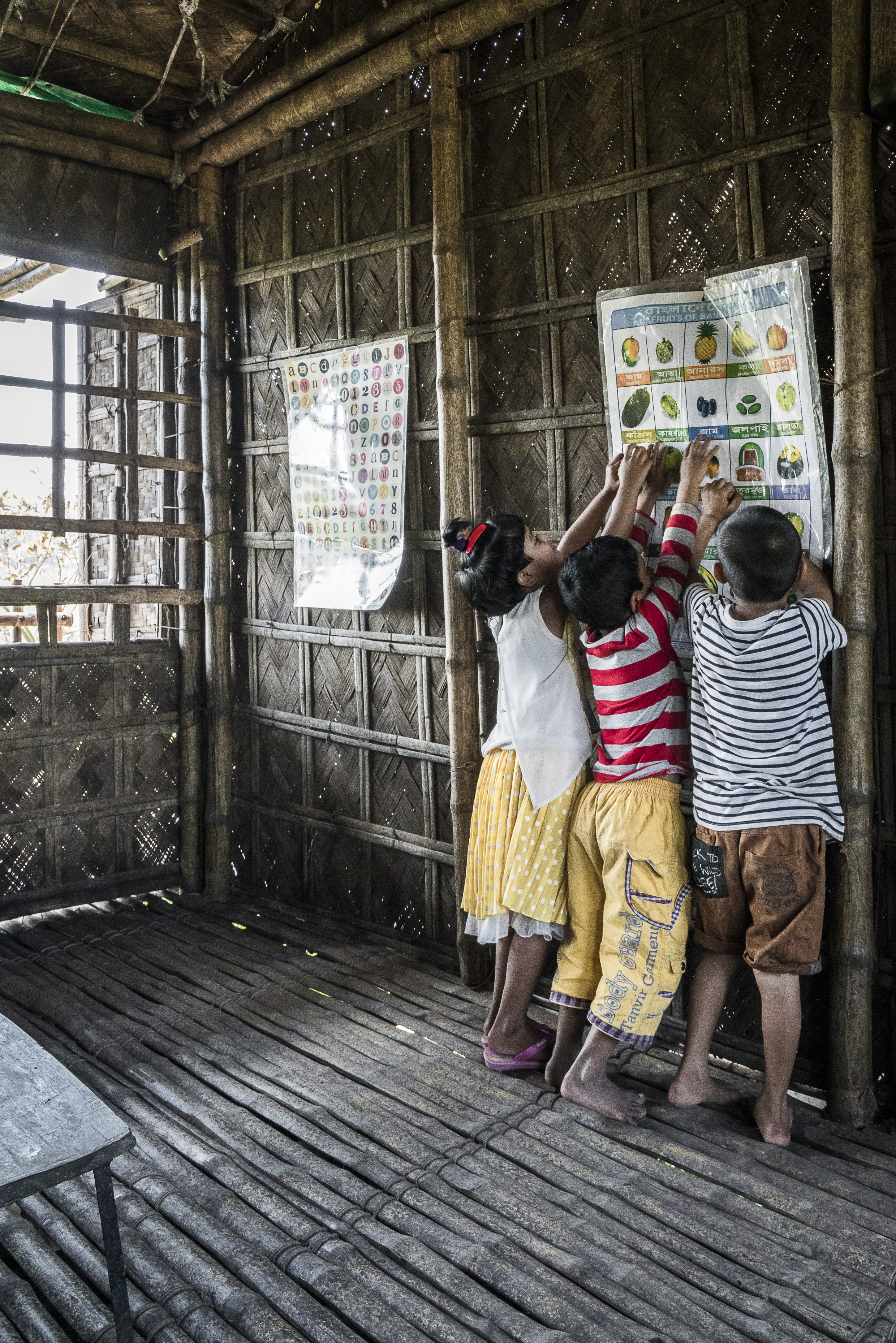 Educational posters are hung on the classroom walls. The use of bamboo allows light and air to penetrate the building, while keeping the heat out.