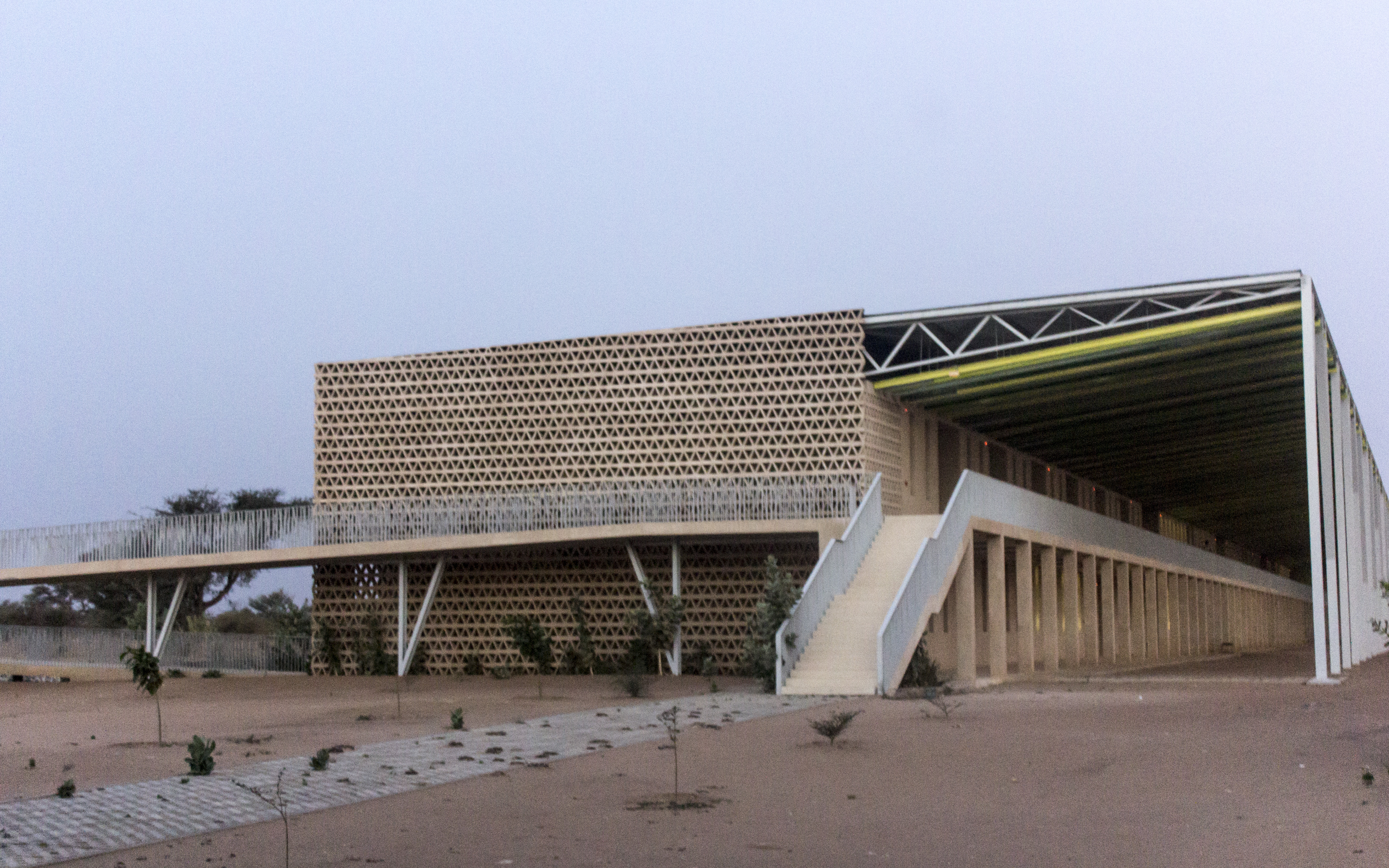 The building is covered with a large double roof and a great lattice on the southern façade, which prevent direct solar radiation and permit air circulation.