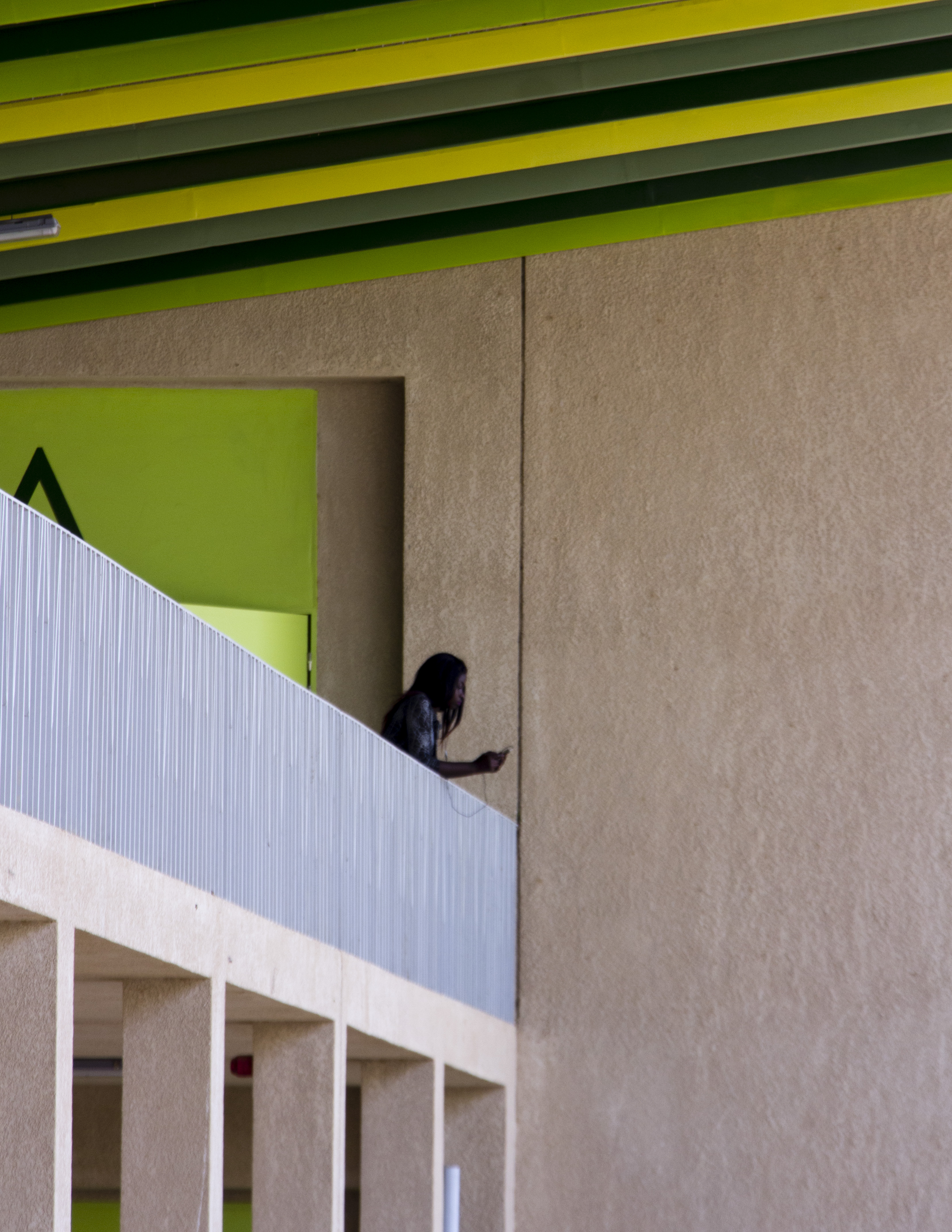 Young woman leaning against the exterior corridor railing.