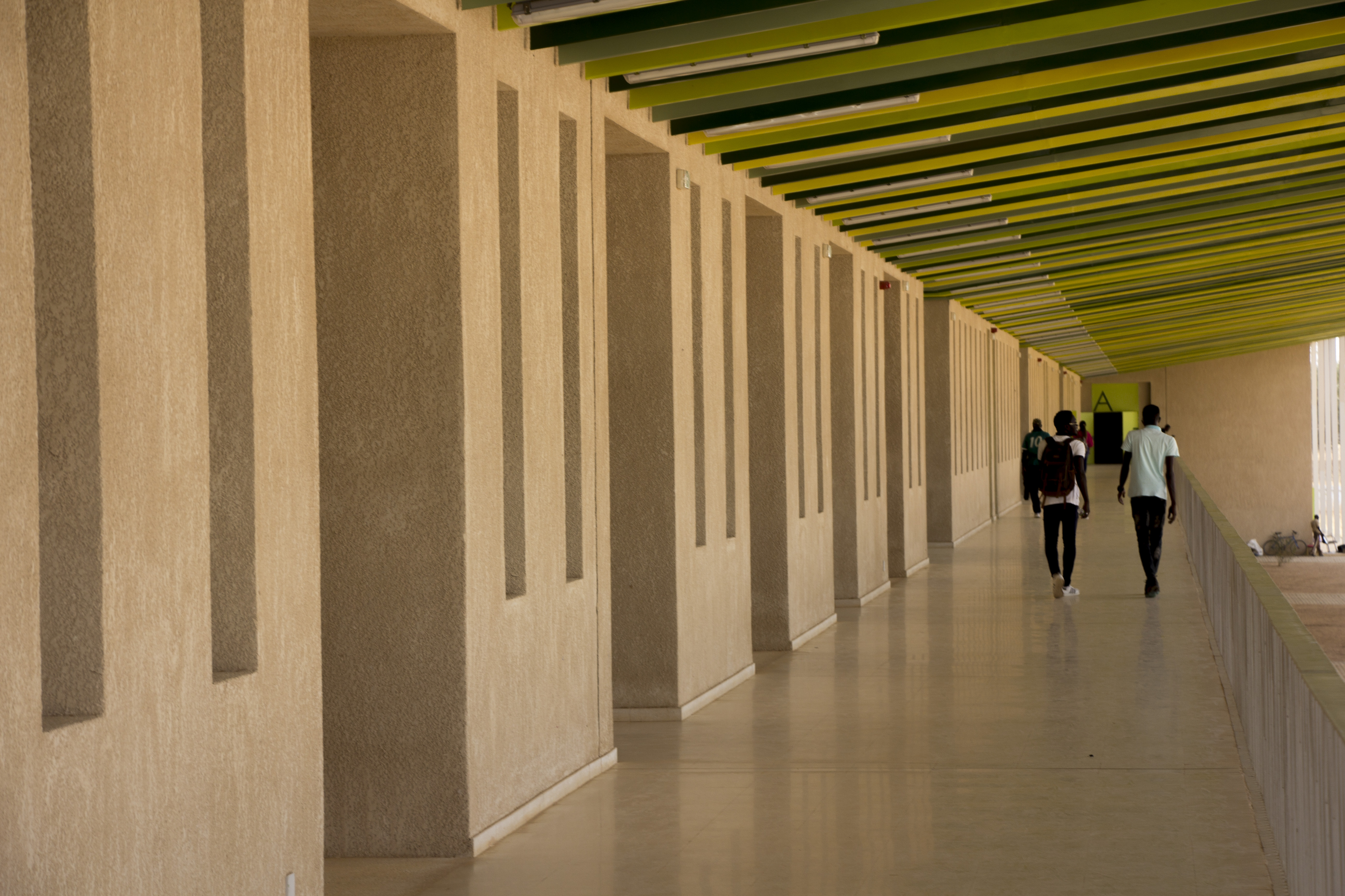 Corridor on the upper level, shaded by the overhang and connecting the different spaces.