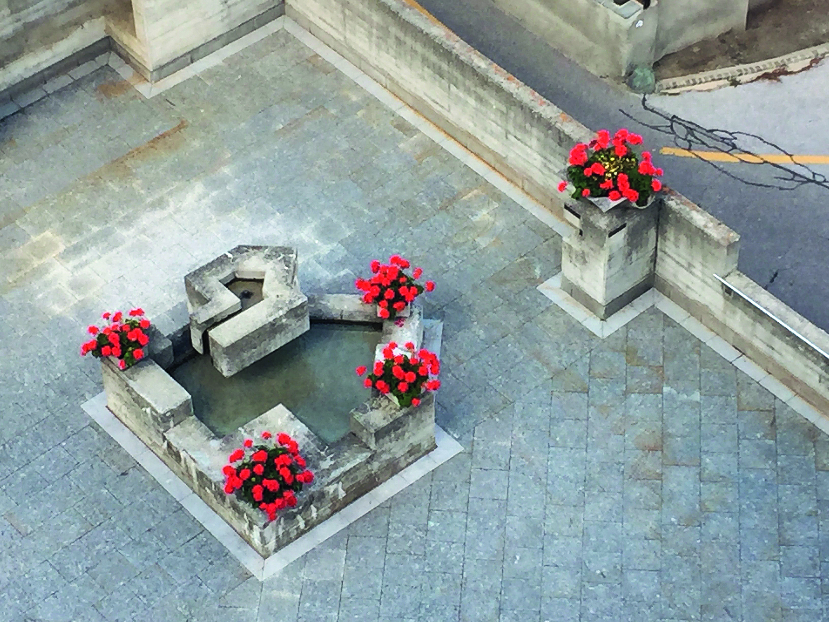 Brunnen und Abfallkübel aus Sichtbeton, entworfen vom international renommierten Künstler Walter Maria Förderer und verziert von der Dorfgemeinde.