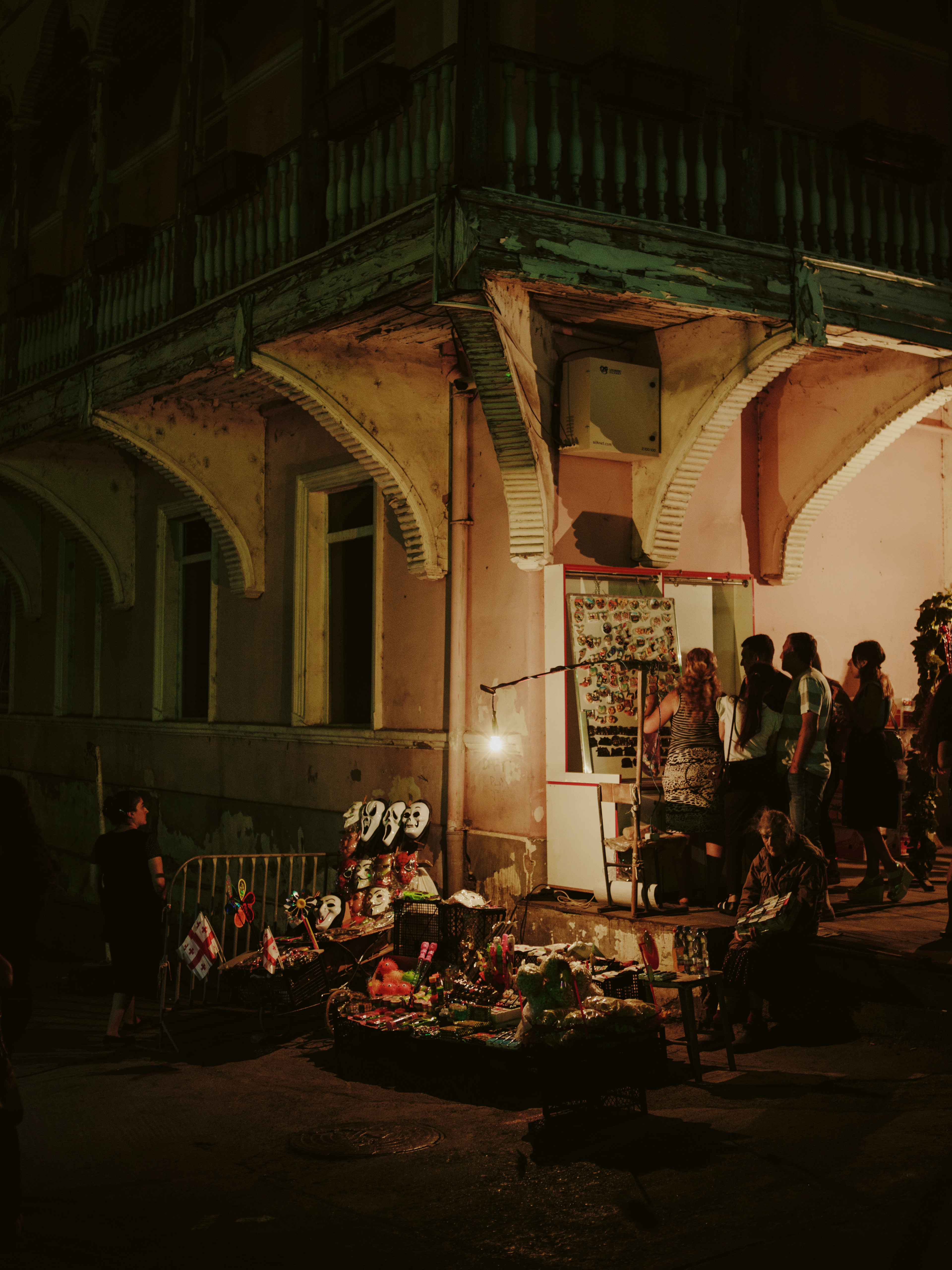 Commerce informel dans le quartier historique et touristique de Sololaki, au pied d’une ancienne demeure dotée d’un typique balcon en bois ouvragé et peint.