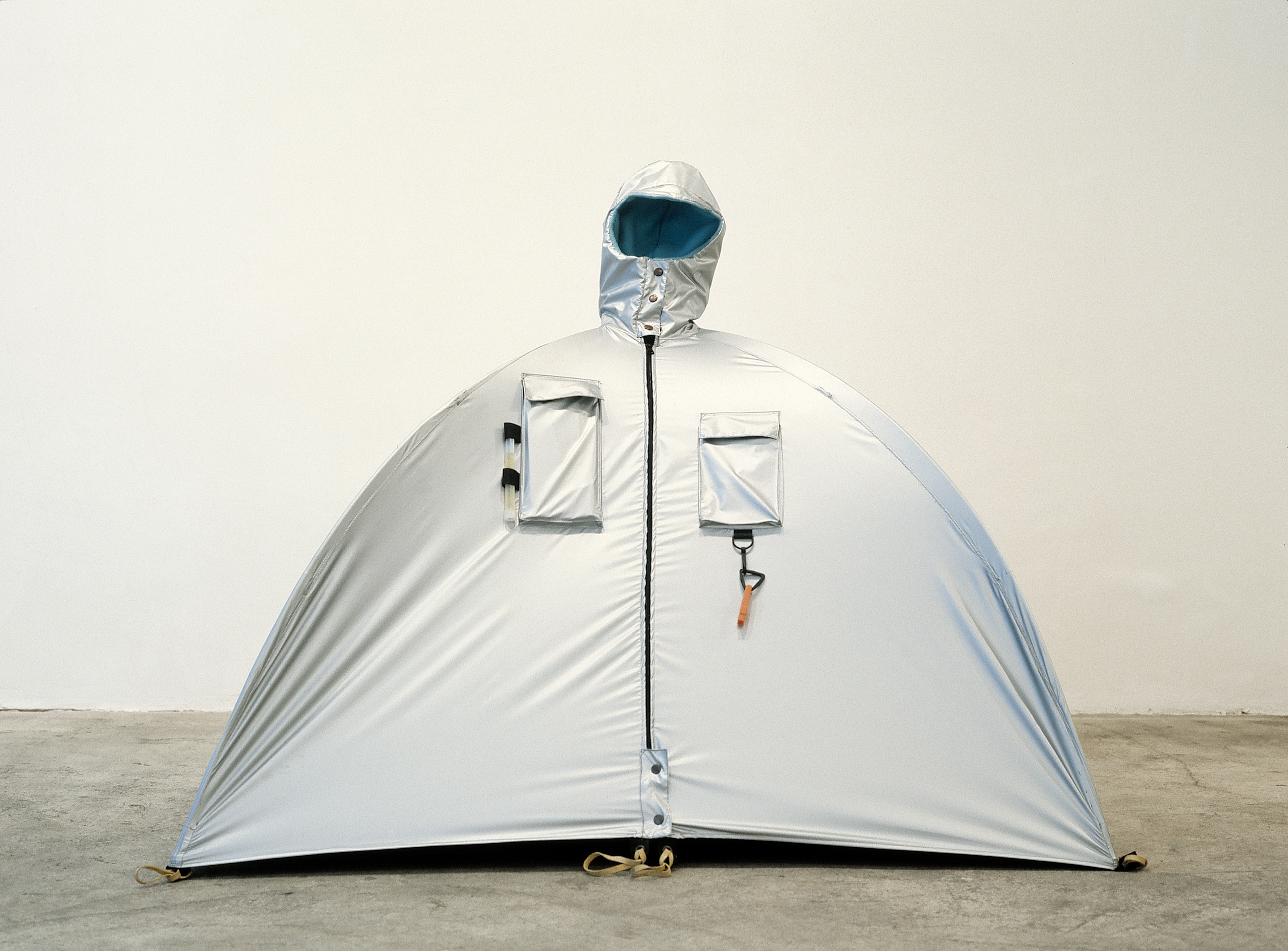 Refuge Wear – Habitent, 1992/1993;  Aluminiumbeschichtetes Polyamid, zwei Teleskopstangen aus Aluminium, Trillerpfeife, Kompass, 125 x 125 x 125 cm. Zur Verfügung gestellt von Lucy + Jorge Orta, ADAGP