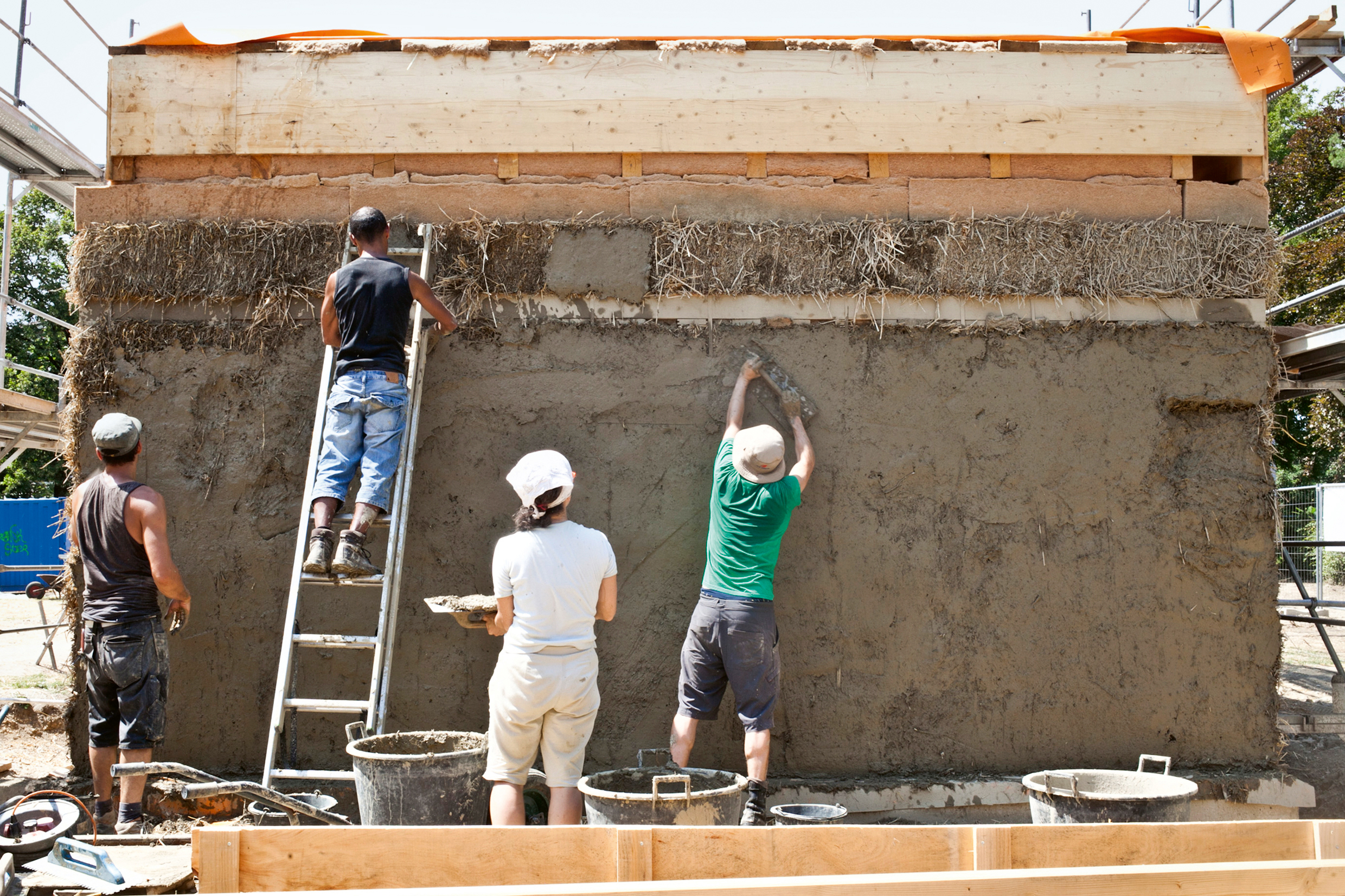 Anwohner verputzten die Strohballen der Fassade mit Lehm.