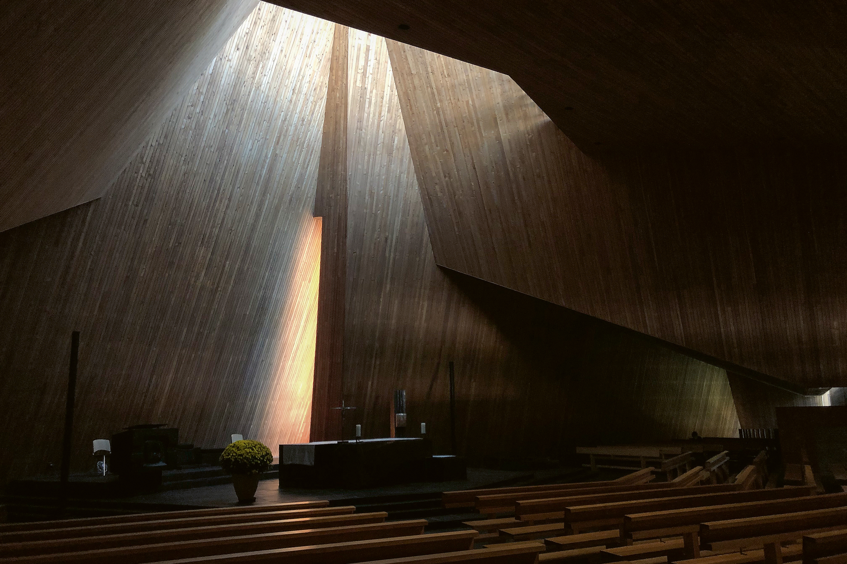 Durch versteckte Fenster dringt das Tageslicht in den hohen Altarbereich der Kirche Maria Krönung in Zürich Witikon. Die seitlich anschliessenden, niedrigen Bereiche verschwinden im diffusen Halbdunkel und unterstreichen die mystische Atmosphäre.
