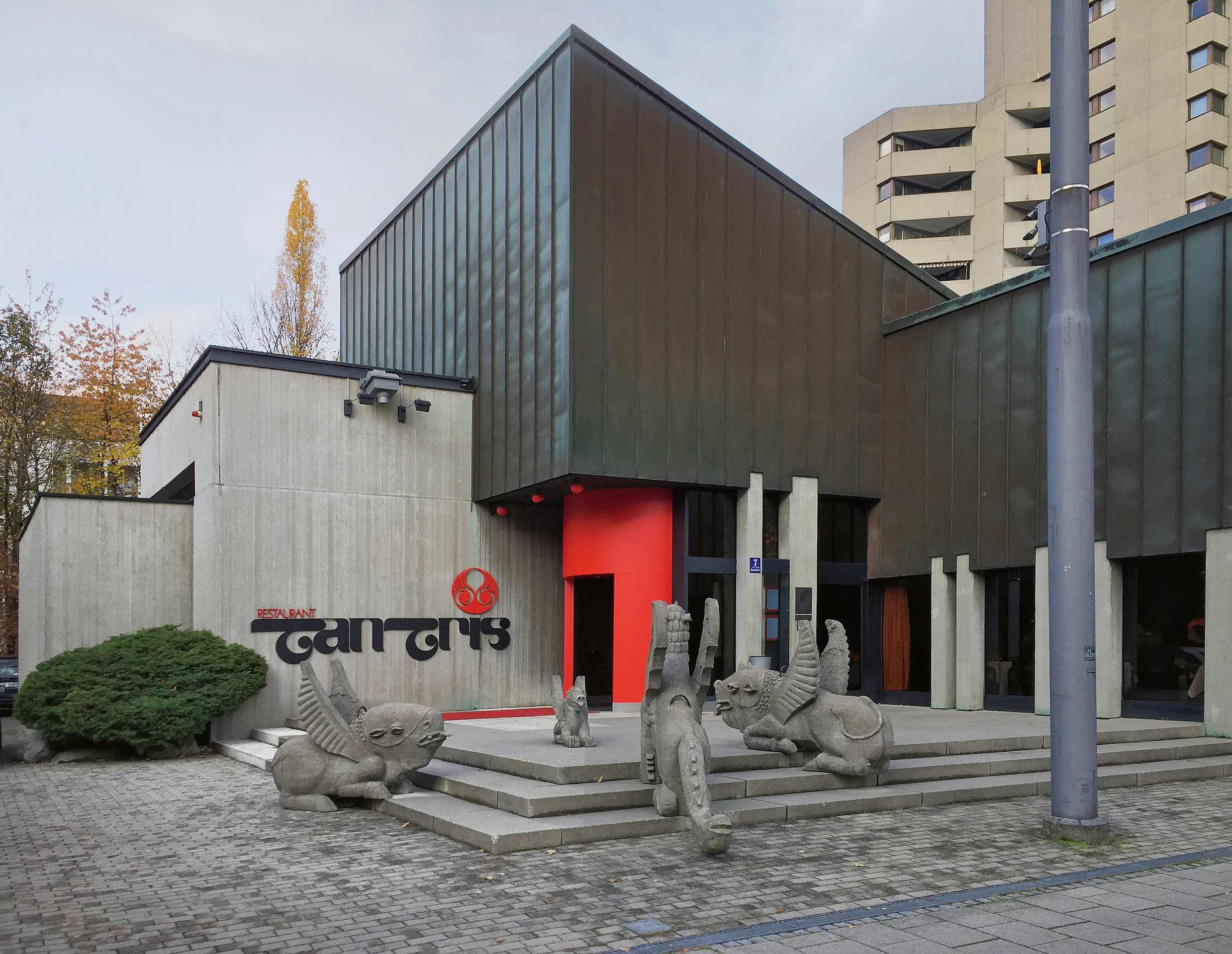 Auf dem Vorplatz des Restaurants «Tantris» lagern Betonskulpturen von Bruno Weber. Die rote Eingangstonne ist als Tor zu einer anderen Welt inszeniert.