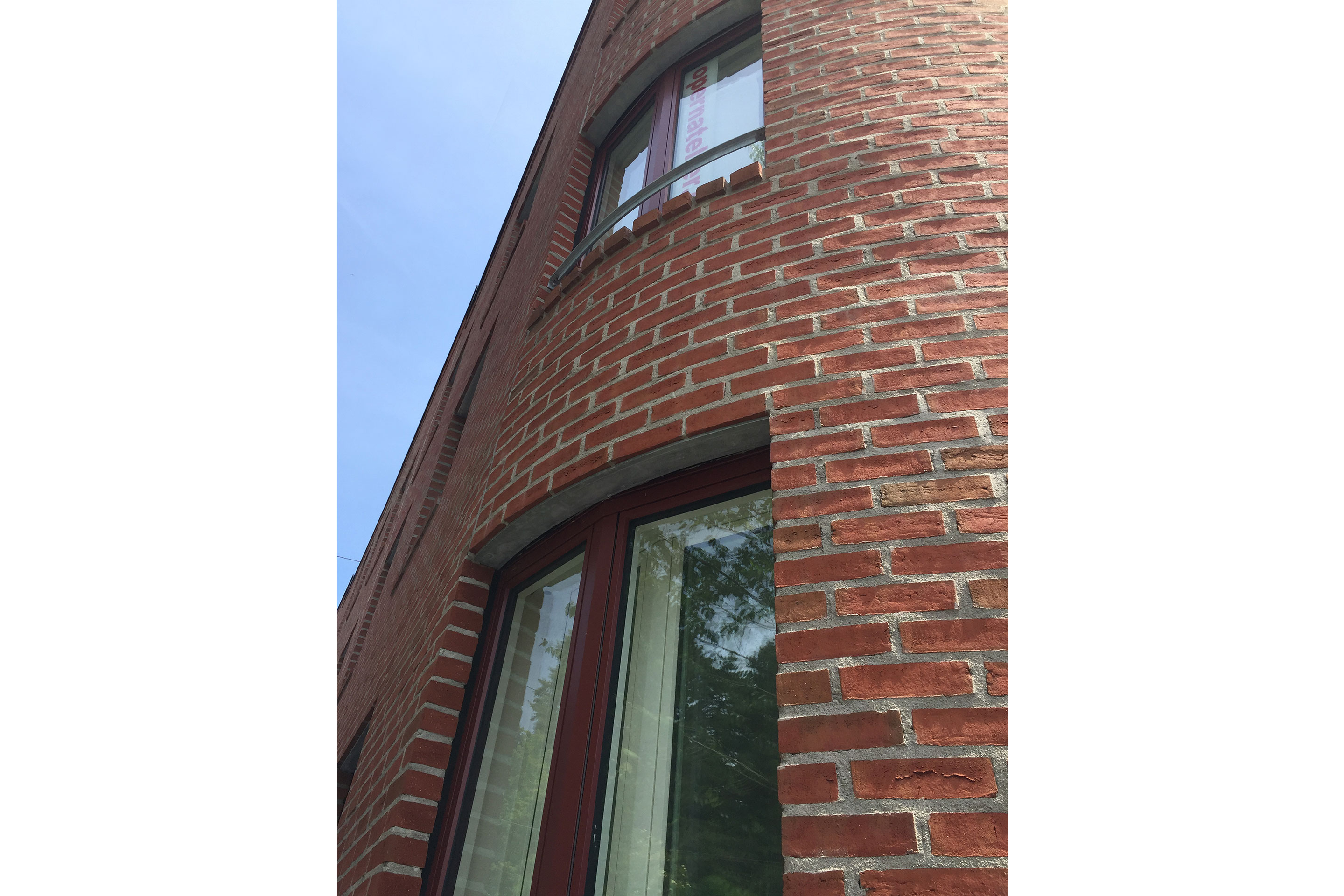 Ein elegantes Detail: Nur von unten sichtbare Stahlzargen überbrücken die Fensteröffnungen im Mauerwerk und dienen als Konsole für die erste Steinreihe oberhalb.