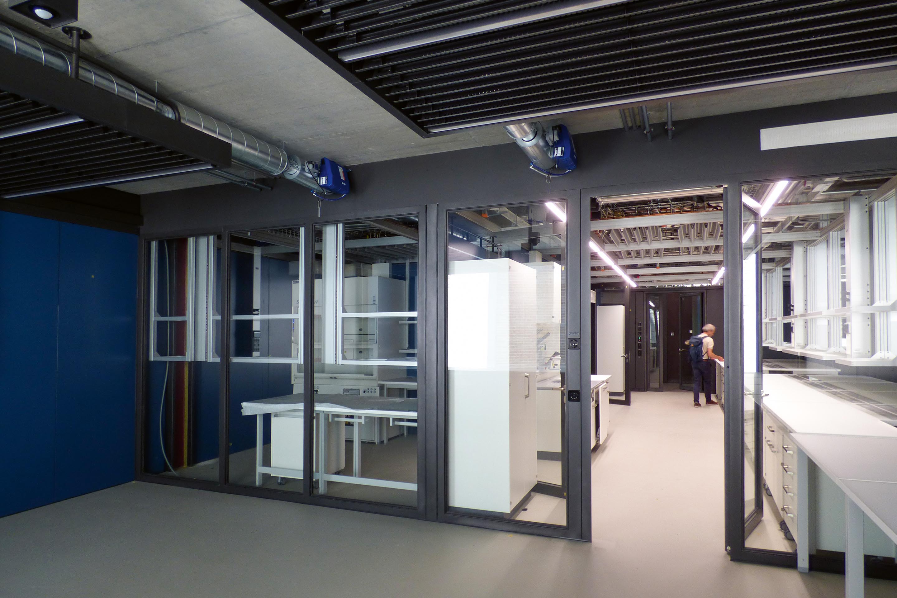 Je tiefer man ins Gebäude eindringt, desto mehr öffnet sich die Gebäudetechnik respektive die Leitungsführung. Ist sie in der Eingangshalle noch verborgen, zeigen sich in den Fluren an der Decke schon punktuelle Technikelemente. In den Laboren sieht man die Leitungen an der Decke. Aber auch eine Mischung ist möglich, etwa in der Auswertezone der Labore.
