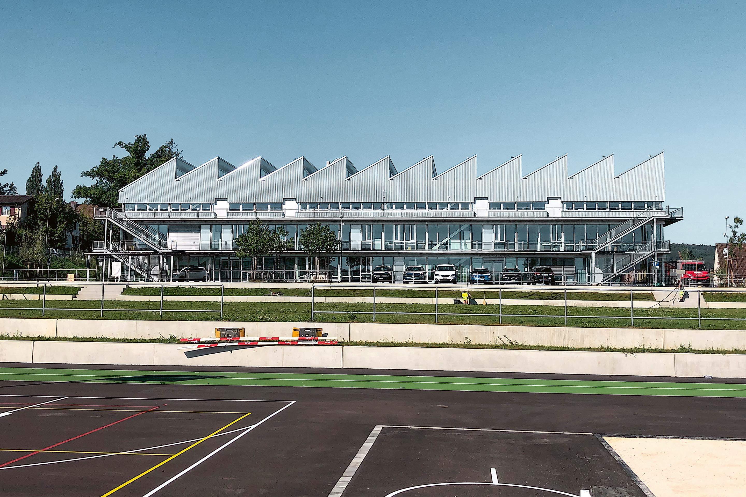 Ostansicht der neuen Sekundarschule in Laufen. Mit rund 2650 m2 Grundstücksfläche beansprucht der Neubau  etwa gleich viel Platz wie das davor liegende Sportfeld und bietet Platz für 18 Klassen.