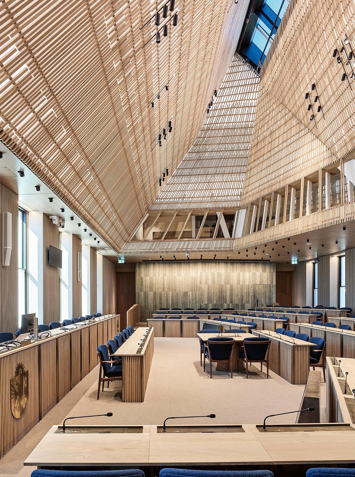 La nouvelle salle du Grand Conseil est coiffée par un spectaculaire «dôme» polyédrique fonctionnant comme une lanterne. La résille de bois à travers laquelle se diffuse la lumière produit une subtile impression de vibration.