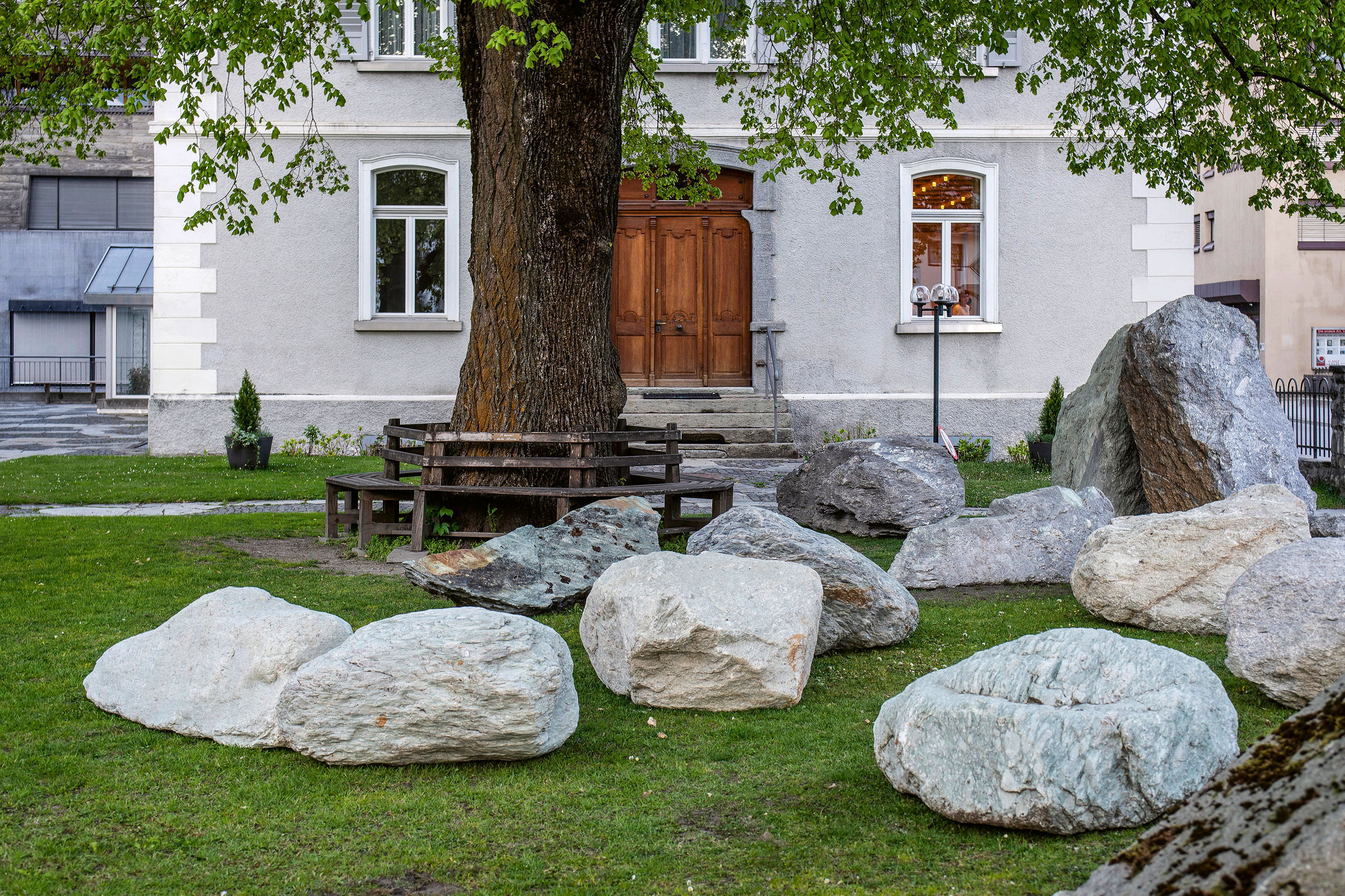 Unter der grossen Linde vor der katholischen Kirche geben verschiedene Vertreter des Ilanzer Verrucano-Steins Einblick in tiefe, uralte Erdschichten. Ihre Präsenz überrascht und lädt zum Sitzen und Spielen ein.