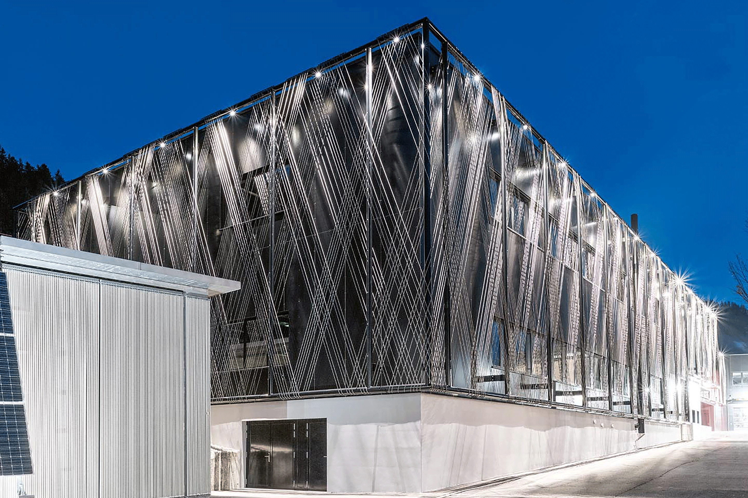 Punktuelle LED-Leuchten beleuchten die Seilfassade der Jakob Rope Systems AG in Trubschachen BE. Mittlerweile wurde die Halle nochmals erweitert und nimmt nun auch die Habegger Seilzugtechnik auf.
