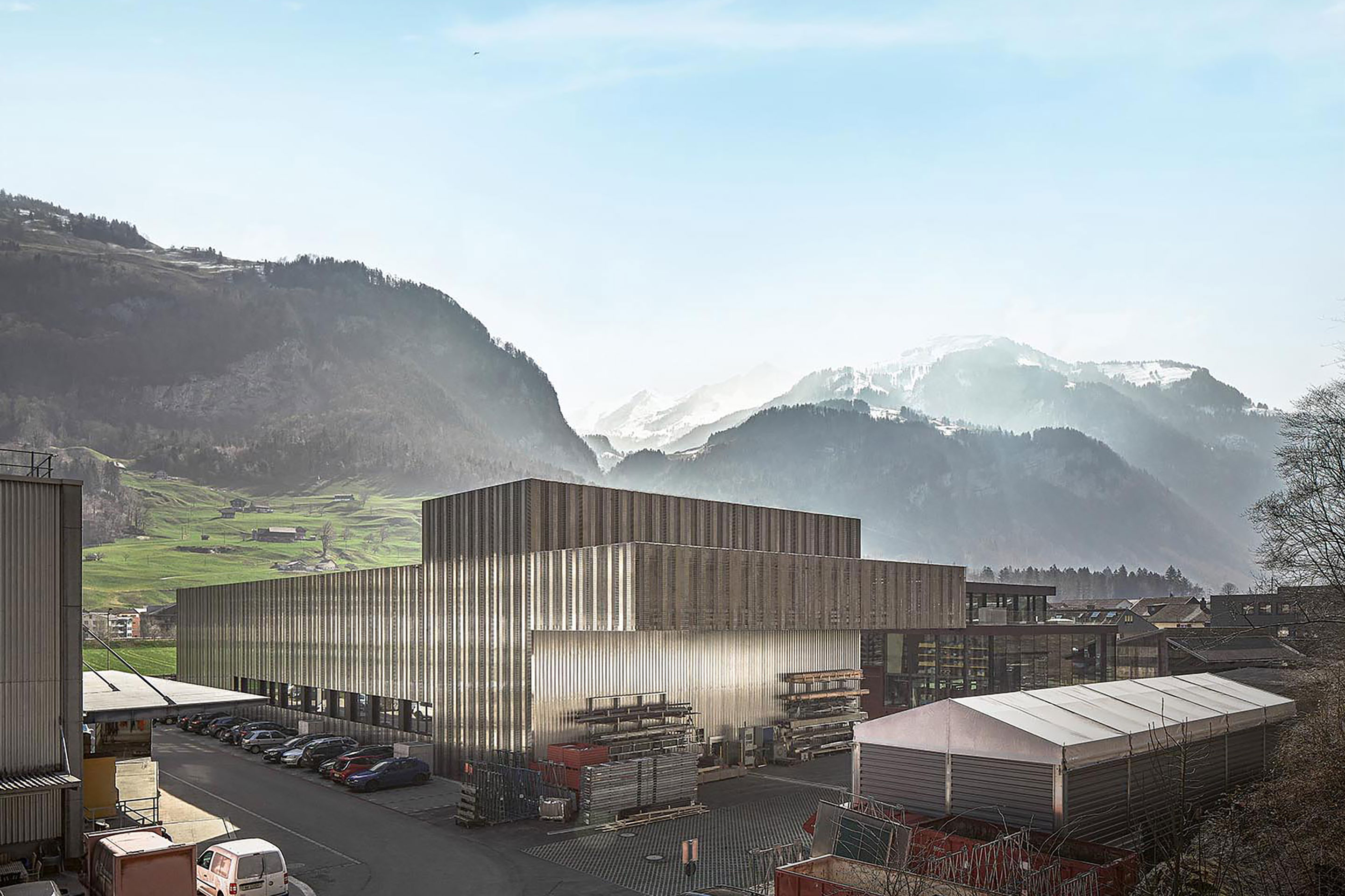 Verschiedene Dekore der Edelstahlpaneele zeigen  eine mögliche Vielfalt der Blechbearbeitung. Nur wo nötig durchbrechen Fenster die stählerne Hülle. Selbst an der rückseitigen Anlieferungszone ist die Edel­stahl­fassade im auskragenden Dachbereich fortgesetzt.