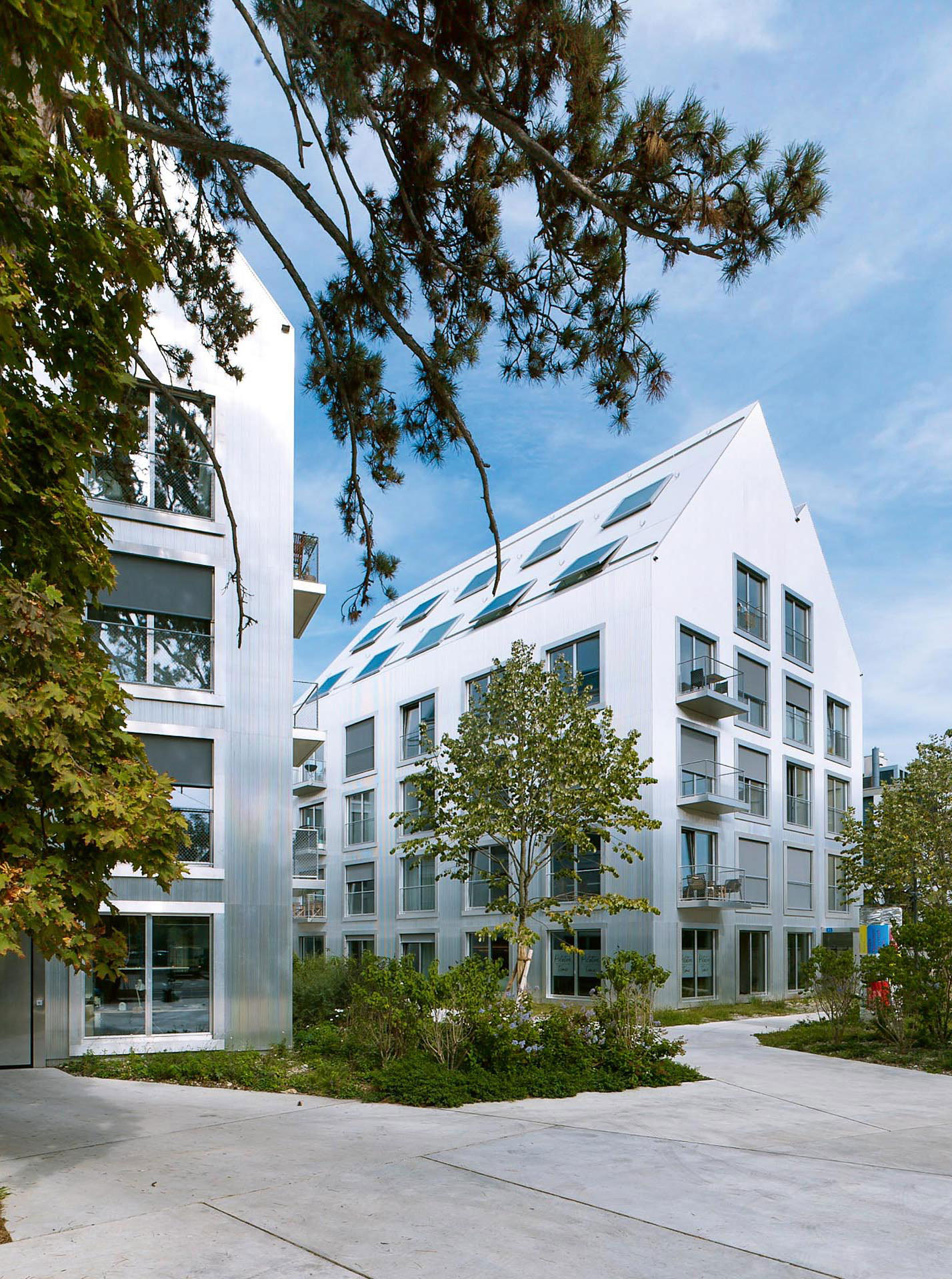 Das Areal öffnet sich in die Tiefe, Fassaden aus gewelltem Aluminium umhüllen die Neubauten.