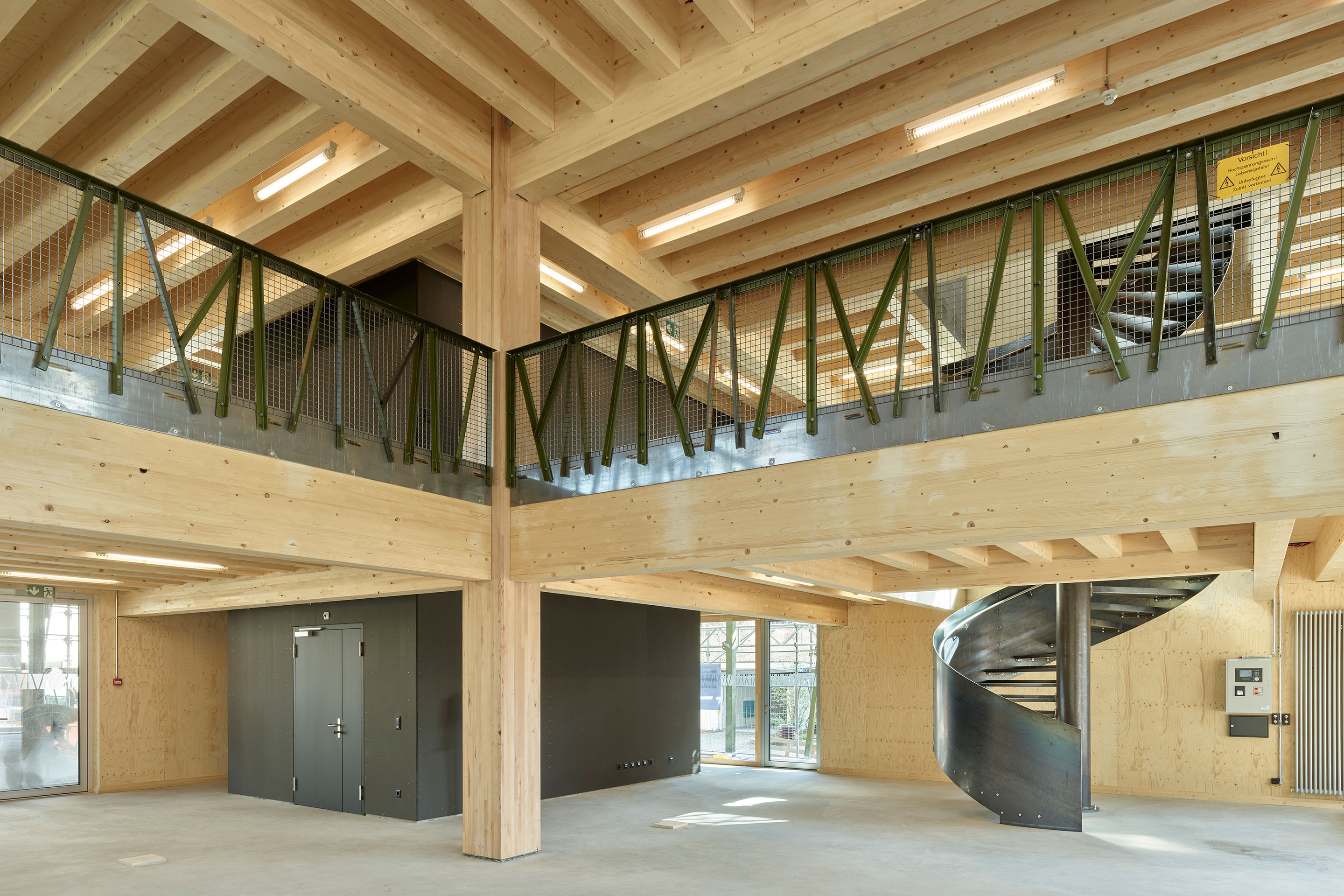 Blick vom Erdgeschoss in den Galeriebereich. Die zentrale Stütze aus hochfestem Laubholz (Buche, Stabschichtholz, Querschnitt 480 x 480 mm) stammt aus der Produktion von Fagus Suisse. Die komplette Balkenstruktur der Decken ist sichtbar belassen.