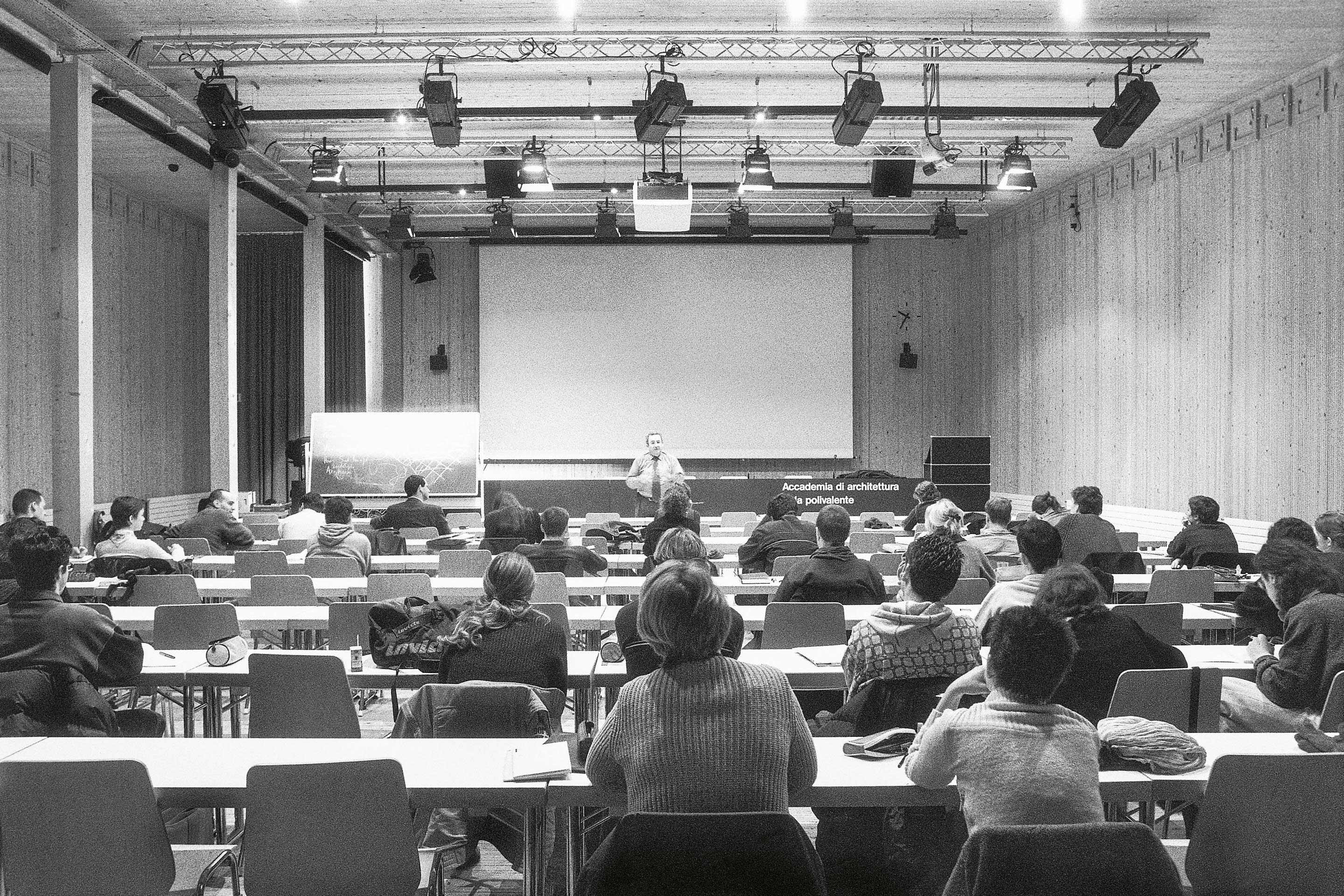 La sequenza di  immagini racconta la metamorfosi dell’edificio: da aula polivalente provvisoria a biblioteca AAM a Mendrisio, lo smontaggio a cura di armasuisse e infine la trasformazione in palestra a Genestrerio.
