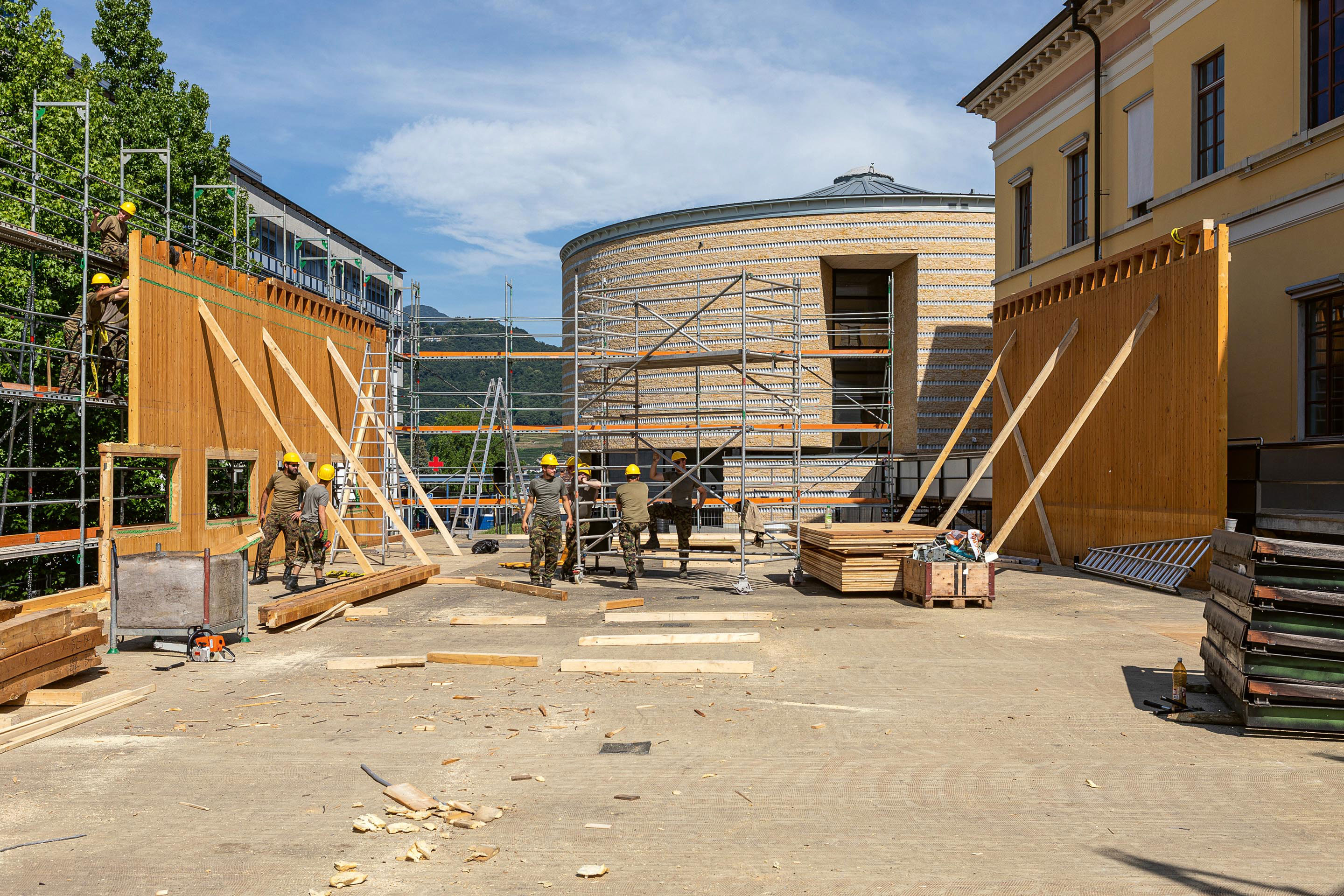 La sequenza di  immagini racconta la metamorfosi dell’edificio: da aula polivalente provvisoria a biblioteca AAM a Mendrisio, lo smontaggio a cura di armasuisse e infine la trasformazione in palestra a Genestrerio.