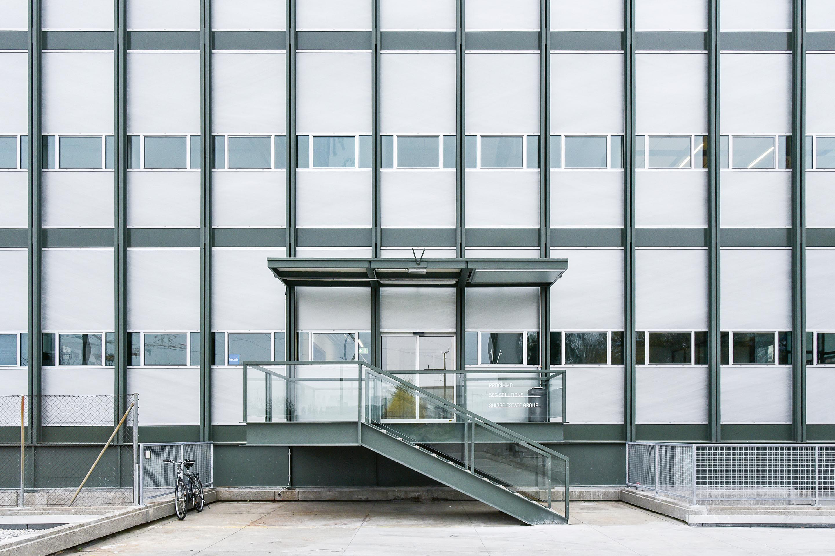 L’exosquelette, fait de doubles cadres porteurs en acier, est bien visible dans sa robe vert olive. Il contraste avec la blancheur de la façade modulaire en aluminium et Thermolux.