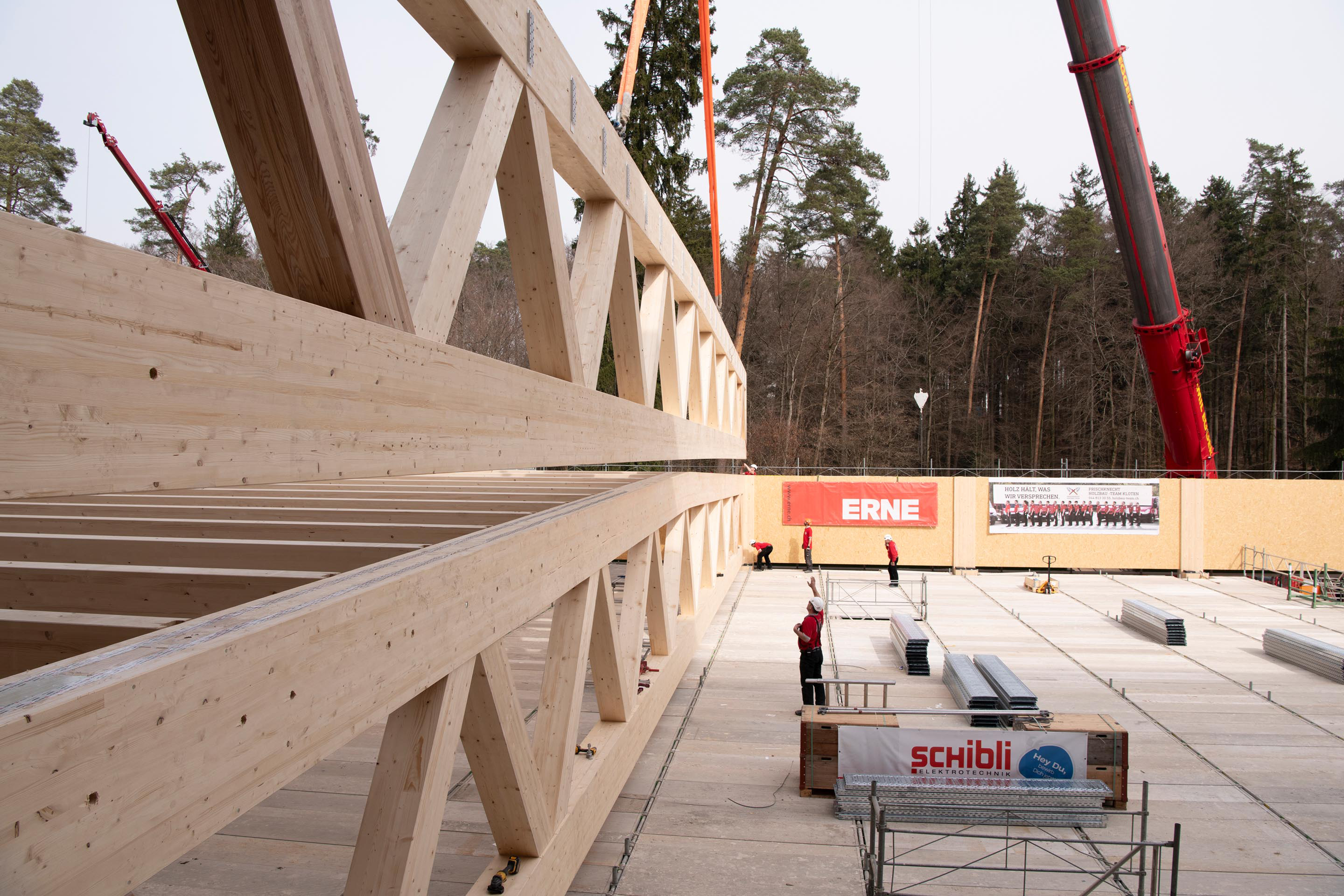 Einer der 35.6 m weit spannenden Fachwerkträger aus Holz wird eingebaut. Zwei Träger zusammen bilden einen Zwillingsträger. Die Lage, wo die Tragseile des Krans in den Trägerknoten angeordnet werden durften, gab der Ingenieur Walter Bieler vorab an.