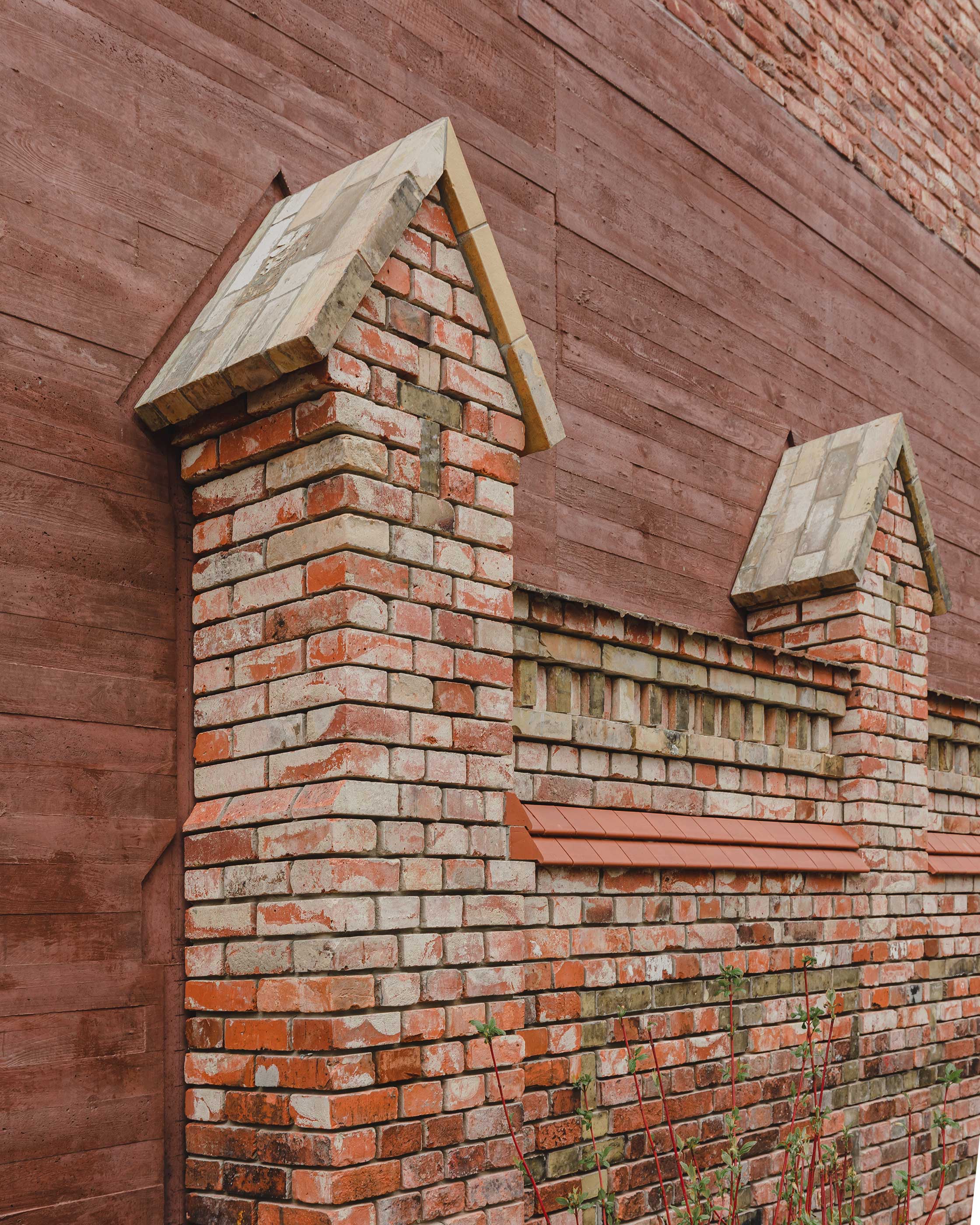 Die Aussenwand des Gebäudes verschmilzt mit einer bestehenden Friedhofsmauer.