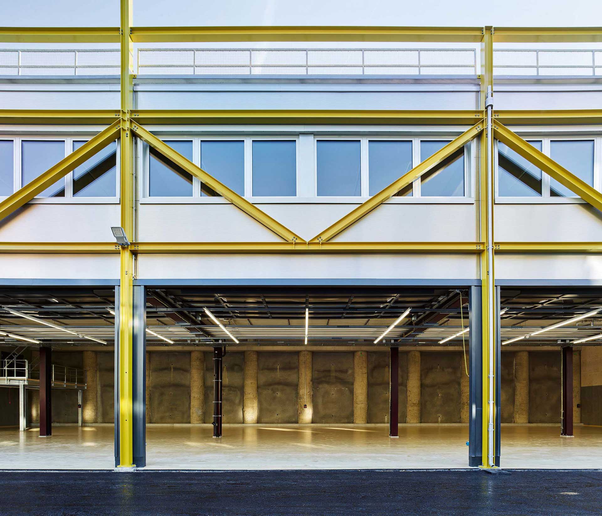 Blick durch die Garagentore in die Halle mit der hinten abschliessenden, sichtbaren Bohrpfahlwand.