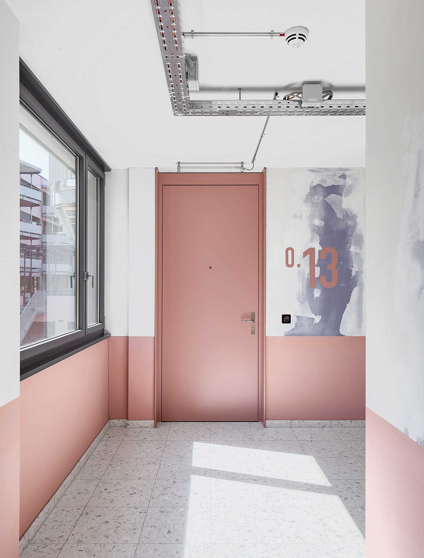 Dans les couloirs, les couleurs des cloisons transparaissent en partie et les découpes dans les murs existants sont volontairement restées visibles.
