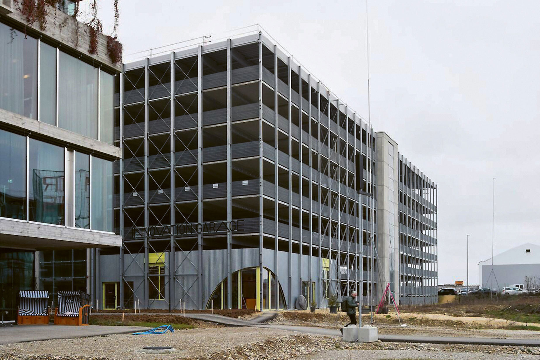 Das Parkhaus West, ein Stahlbau mit Betonböden und eines von zwei zentralen Parkhäusern auf dem Areal, bietet 500 Parkplätze und beherbergt im Erdgeschoss die «Innovation Garage» der Universität Basel; hinter einer thermischen Blechbox befinden sich Büroflächen, Coworking-Spaces und Kreativräume. • Bauherrschaft: Senn Resources; Architektur: Felippi Wyssen Architekten; Fertigstellung: 2021