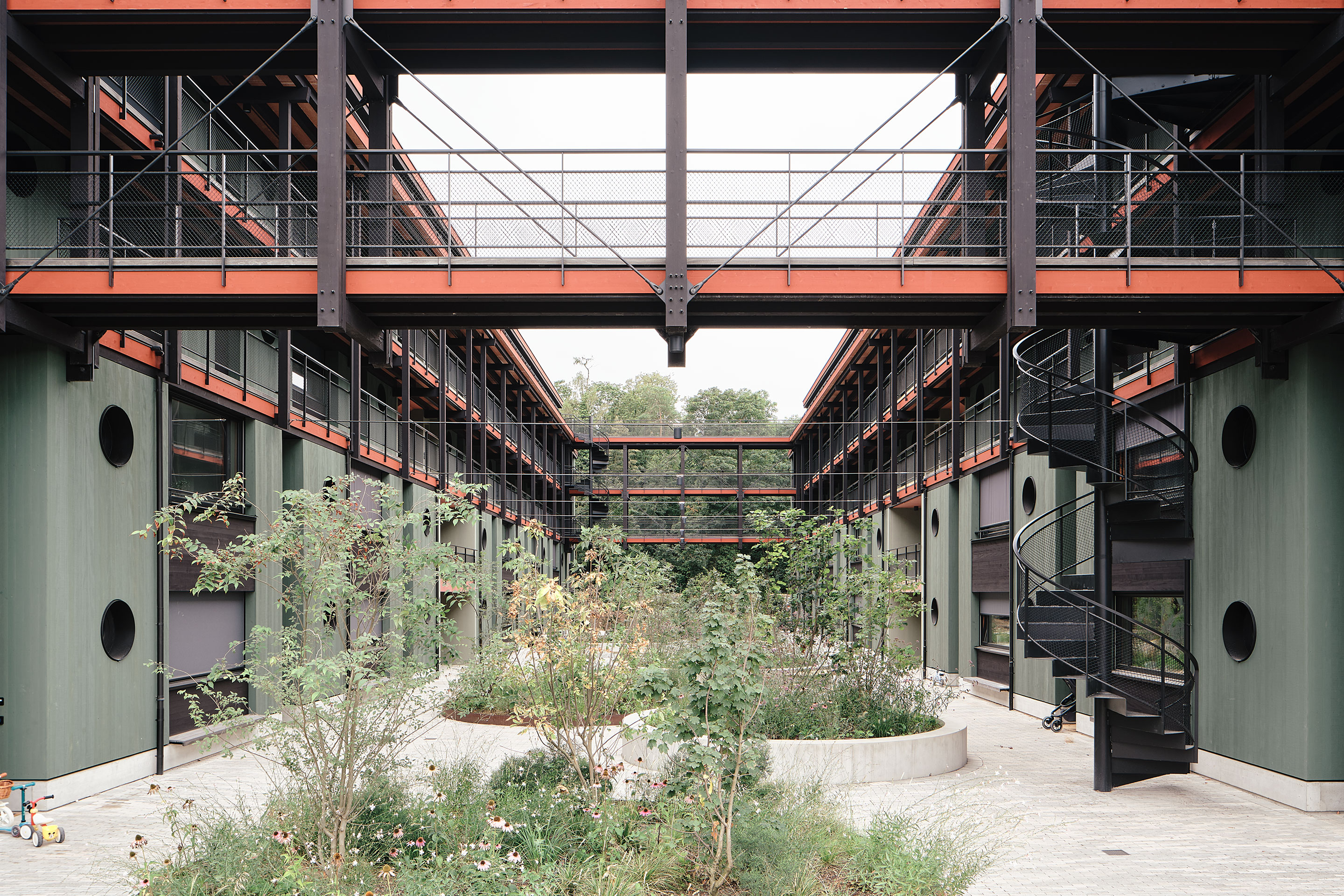 Zwischen den beiden Gebäuden verbinden sich die Laubengänge zu einer Brücke und fassen den Hof ein. -