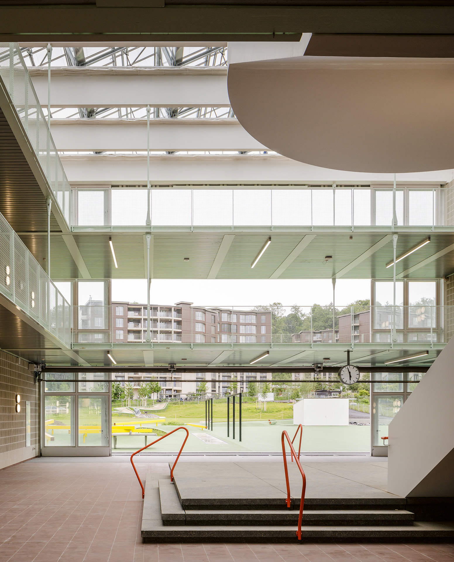 Das dreistufige Plateau im Zentrum des Atriums: Podest, Bühne oder Sockel? Vor der öffenbaren Glasfront: Schulhof, Quartierpark, Wohnsiedlung Guggach II.