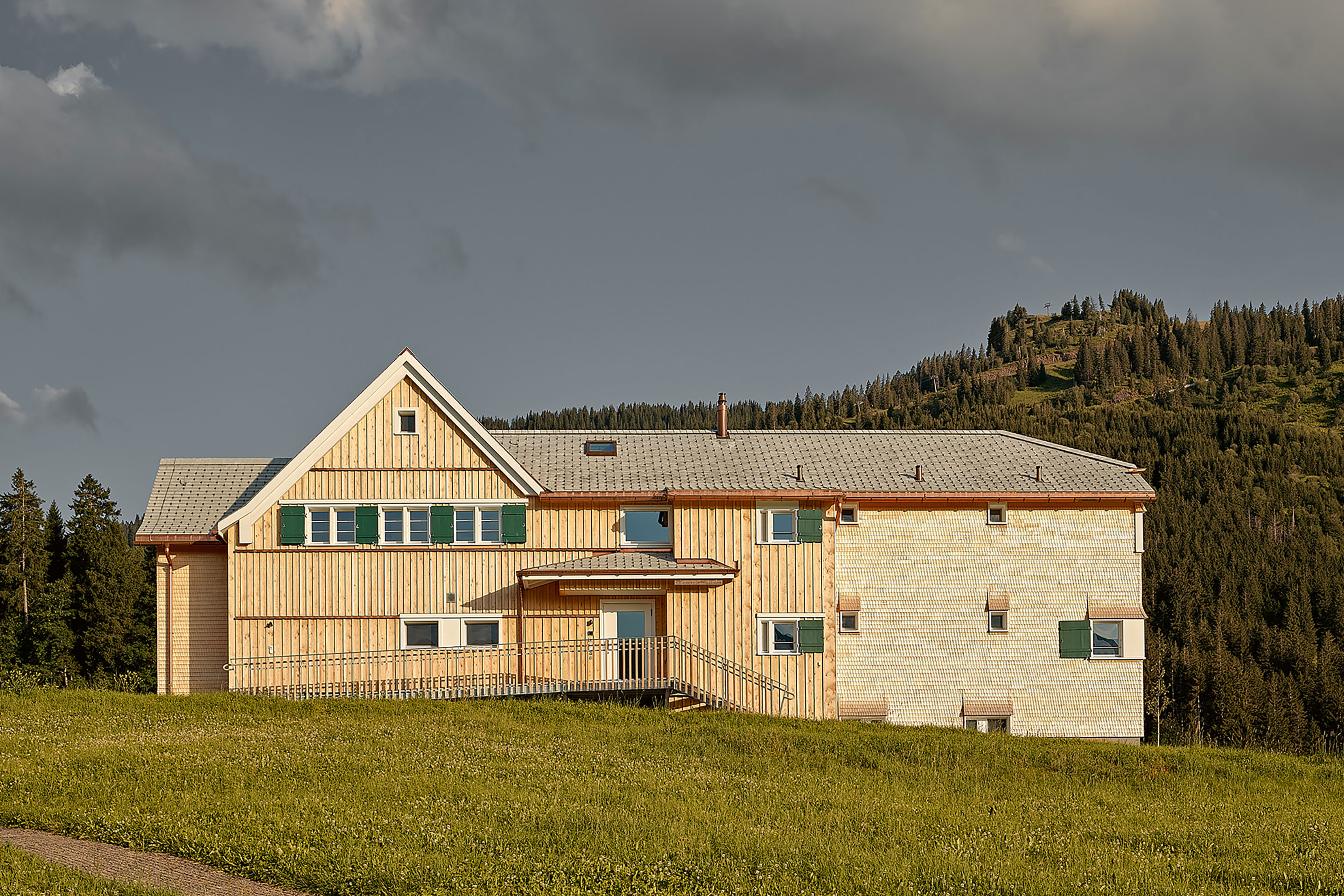 Die Nordfassade des Jennyhaus im Toggenburg leuchtet im abend­lichen Streiflicht. Das helle Gelb des Holzes wird im Laufe der Jahre ergrauen und sich harmonisch in die Umgebung einfügen.