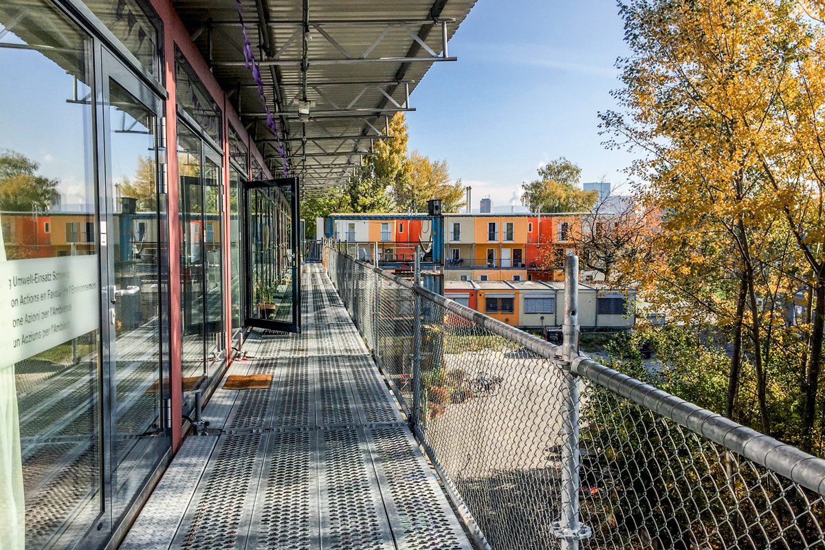 Laubengang der Ateliercontainer des Basislagers mit Blick auf die Asylunterkünfte.