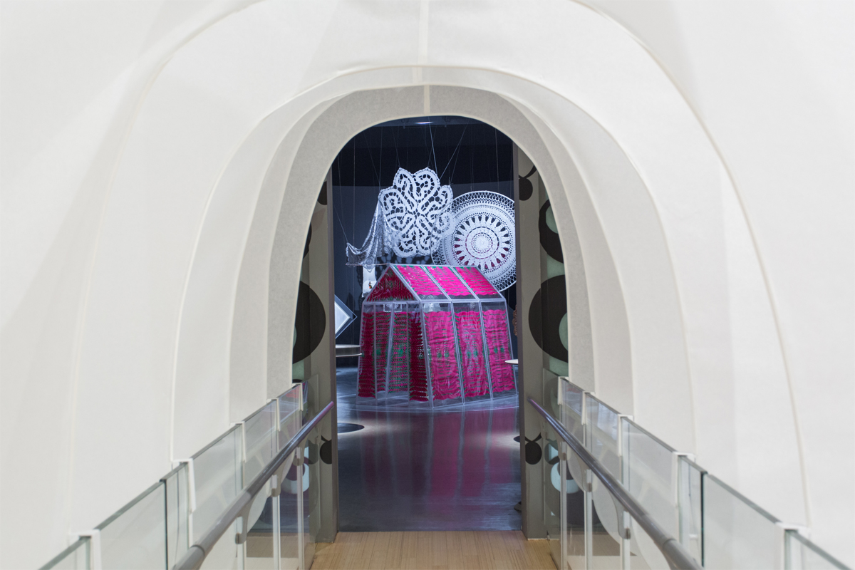 Die mit weissen Segeln markierte Holzbrücke führt zum Ausstellungsraum im 1. Obergeschoss des Triennalegebäudes, in einen geheimnisvoll abgedunkelten Raum mit Objekten aus Kunst und Design.
