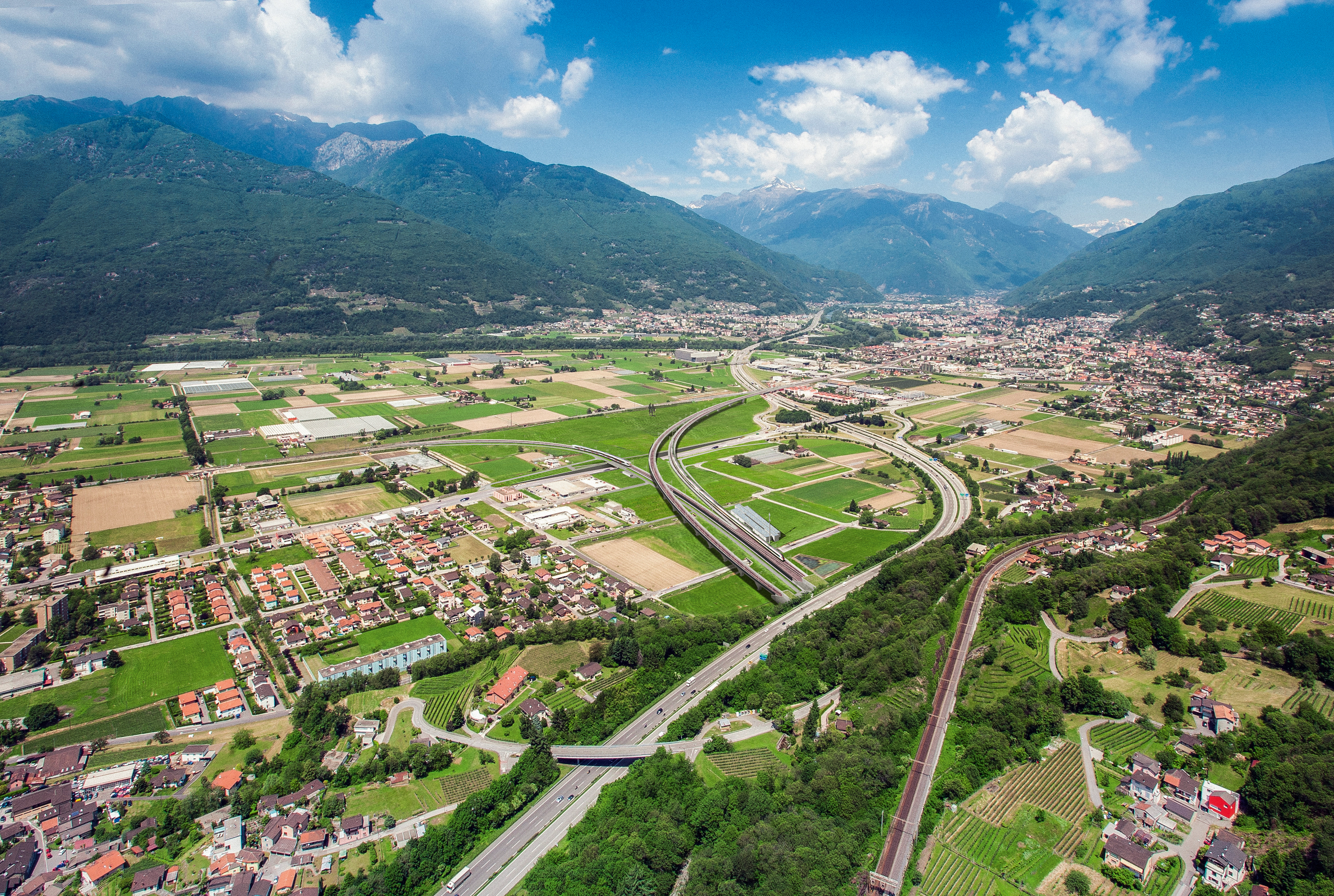 Im Vordergrund die Ceneri-Basistunnelportale. Aus dem linken kommt der Viadukt Lugano–Bellinzona. Der tiefer liegende, parallel verlaufende Viadukt für die Gegenrichtung ist ähnlich gestaltet, konzeptionell aber wesentlich anders.