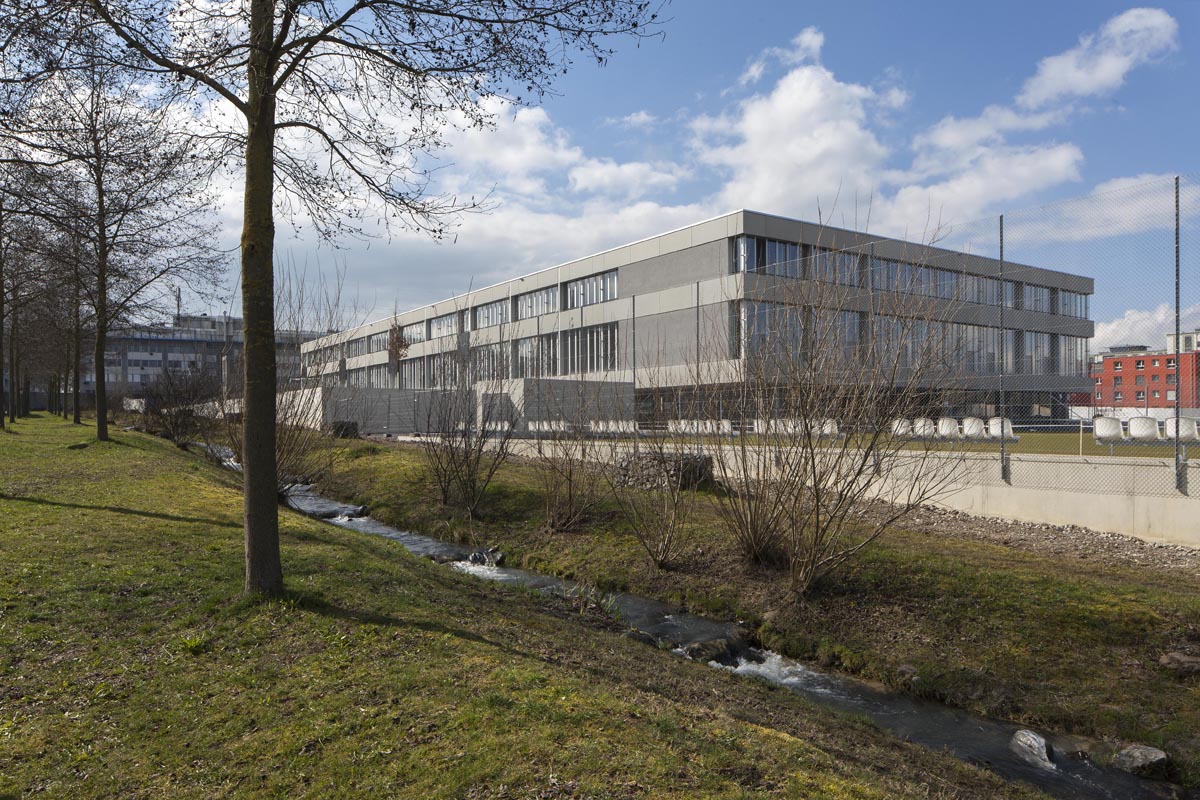 Die Schulanlage Blumenfeld präsentiert sich inmitten lauter fünf- bis siebengeschossiger Wohnbauten kompakt und reduziert. Die Gebäude sind nach den Kriterien des Standards Minergie-P-Eco zertifiziert und erreichen die Ziele der 2000-Watt-Gesellschaft. Für die Raumheizung werden 35 Erdwärmesonden verwin den Untergrund gebohrt, die Abwärme der Duschen und von der Küche wird zum Aufheizen des Frischwassers genutzt und Luftqualitätssensoren sorgen für eine optimale Belüftung.