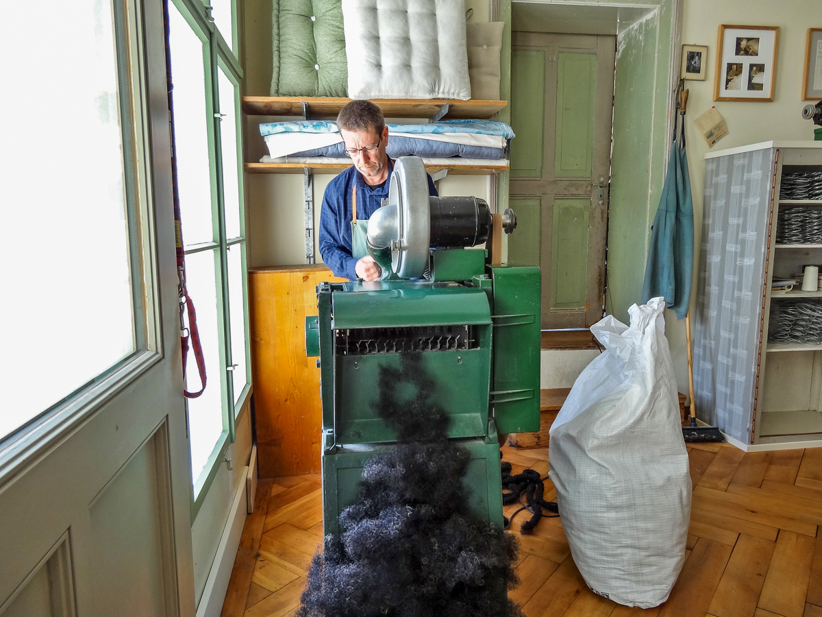 An der Zupfmaschine werden die gedrehten Rosshaarstränge aufgezwirbelt und so für die Füllung vorbereitet. Wird ein ganzer 13-kg-Sack aufgezupft, ist der gesamte Fussboden der Werkstatt mit Rosshaar bedeckt.
