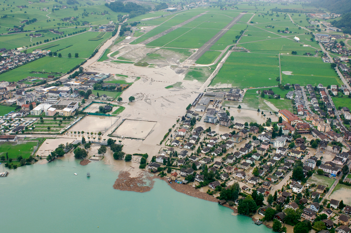 Jahrhunderthochwasser 2005 an der Engelberger Aa mit teilweise kontrolliertem Abfluss: Die Überflutung des Kulturlands (linke Bildhälfte) war in Kauf genommen worden; die Schutzmassnahmen gegenüber dem Siedlungsteil von Ennetbürgen (rechte Bildseite) waren damals noch nicht umgesetzt.