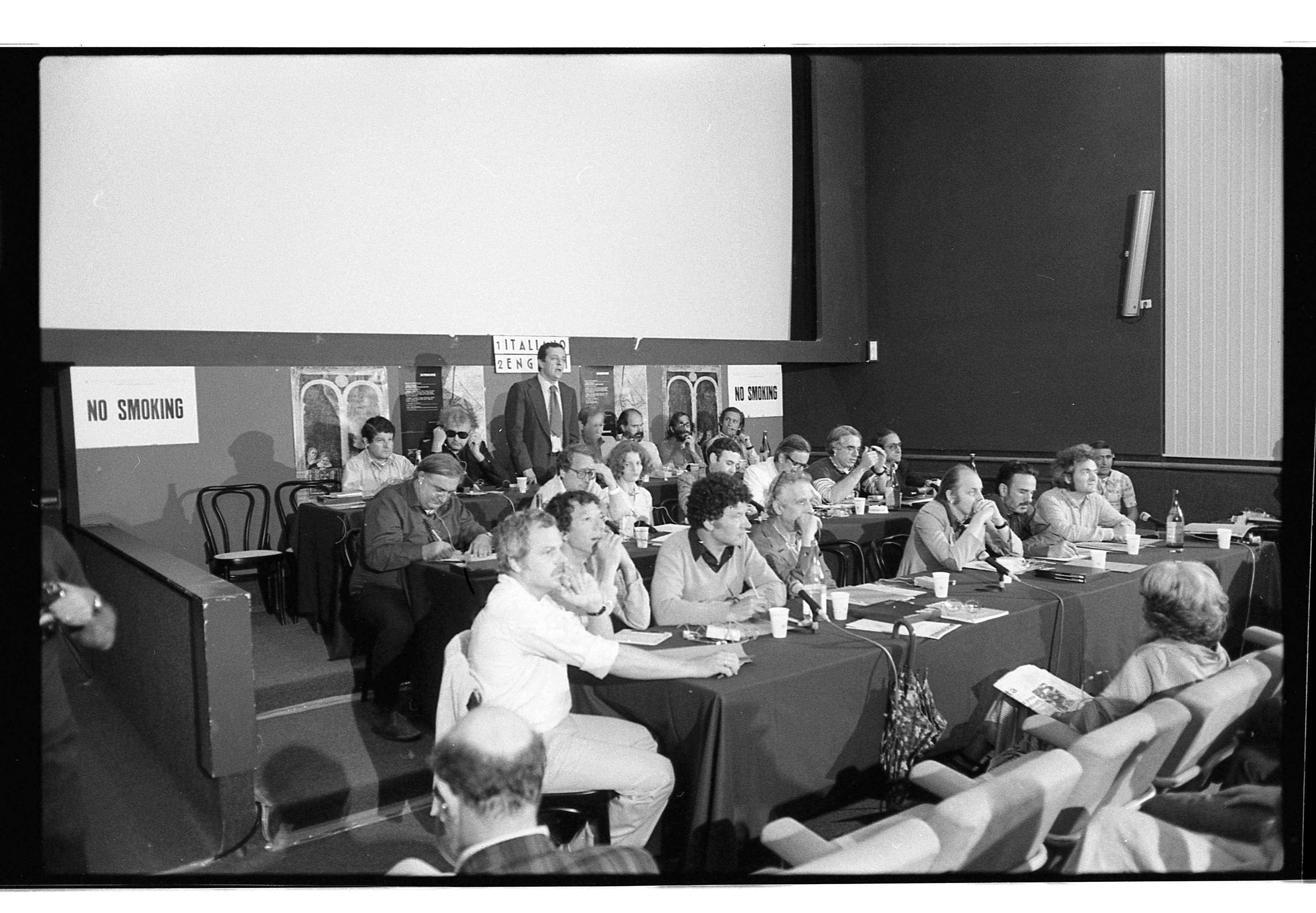 Lors de la Biennale de Venise de 1976, dans le Palazzo del Cinema au Lido, le 1er août 1976, se tient la conférence « Quale movimento moderno ? ». Y participent entre autres Stanley Tigerman, John Hejduk, Carlo Ripa di Meana, Joseph Rykwert, Lucien Kroll, Alvaro Siza, Oriol Bohigas, James Stirling, Robert Venturi, Denise Scott Brown, Emilio Ambrasz, Carlo Aymonino, Peter Eisenman, Robert Stern, Jean Deroche, Paul Chemetov, Aldo Van Eyck, Hans Hollein, Giancarlo di Carlo, Herman Hertzberger, Aldo Rossi.