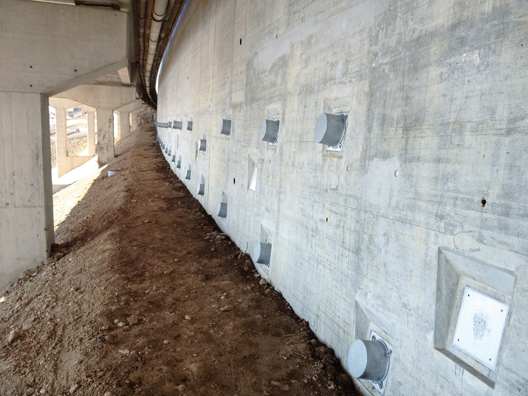 A9 bei Les Curnilles VD : Verstärkung einer talseitigen Winkelstützmauer mit einer vorbetonierten, vorgespannten Nagelwand. Unter der Brücke erfolgten die Bauarbeiten unter erschwerten Bedingungen.