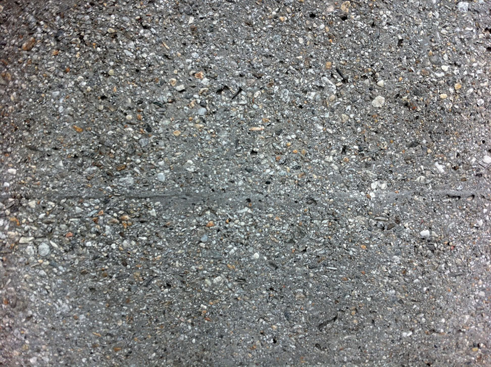 Calcestruzzo parzialmente dilavato della pellicola cementizia ed esposizione degli aggregati rocciosi.