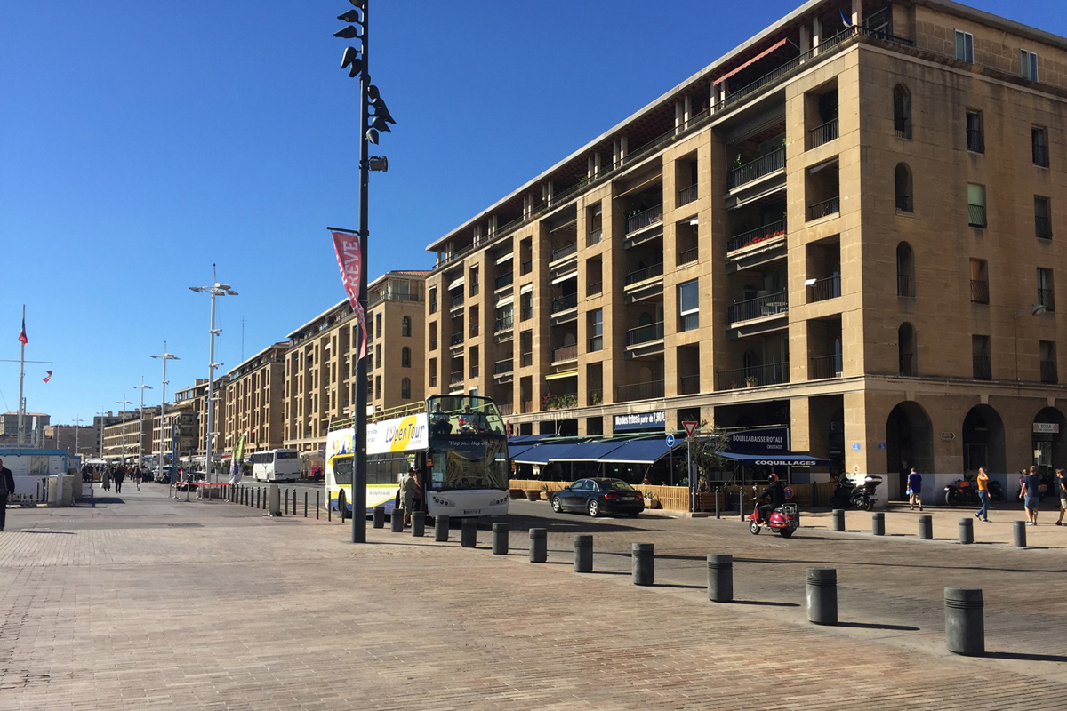 Marseille, Vieux Port: Fernand Pouillons Kolonnaden mit den Balkonen darüber sind massive Steinkonstruktionen. Hinter der Steinfassade der Wohnräume verbirgt sich dagegen eine verlorene Schalung.