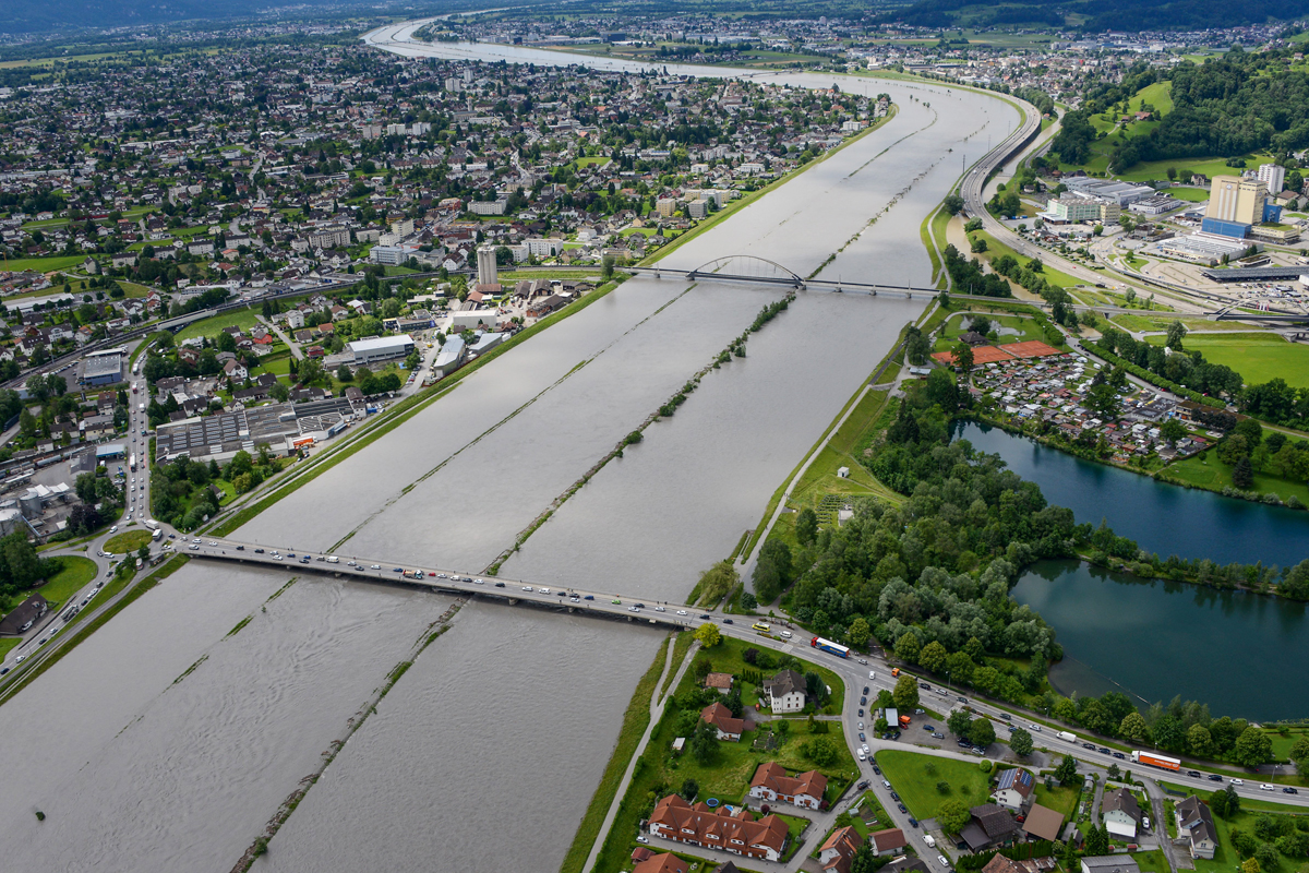 Alpenrhein am 16. Juni 2016: Ab einem Abfluss von 1200 m3/s strömt Wasser aus dem Mittelgerinne in die Rheinvorländer. Auf der linken Seite Lustenau, auf der rechten Seite oben die Autobahn A13 bei St. Margrethen auf dem Hochwasserdamm und gleich dahinter der Rheintaler Binnenkanal, der in den Flusslauf des Alten Rheins mündet und diesen mit Wasser versorgt.