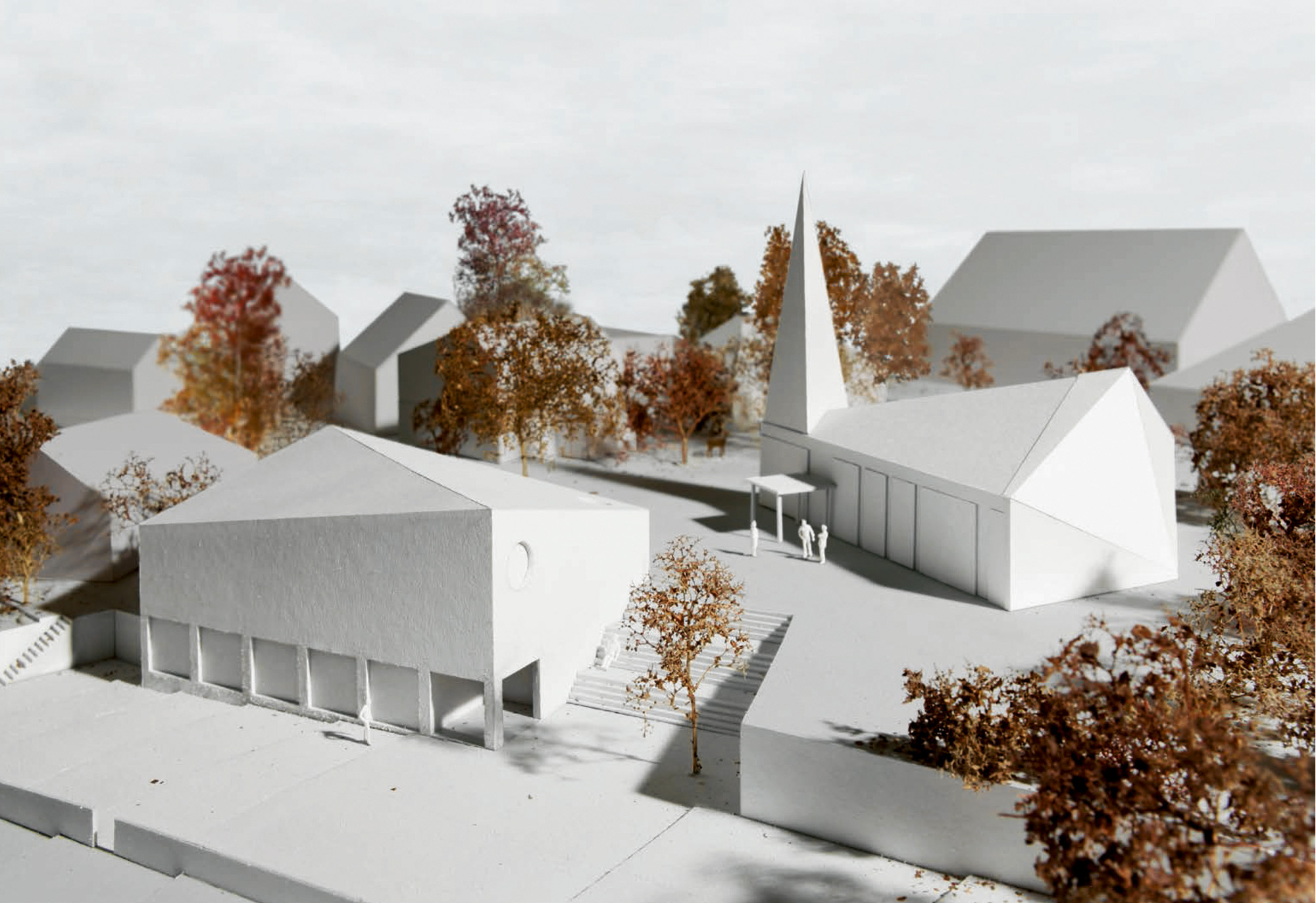 Der Siegerentwurf «Thales» stellt der Kirche mit ihrem experessiven Trapez­grundriss ein präzise gesetztes Volumen gegenüber, das zwischen Fauggersweg und Kirchplatz vermittelt und das zurückgesetzte Grundstück gleichzeitig zum Strassenraum hin öffnet.