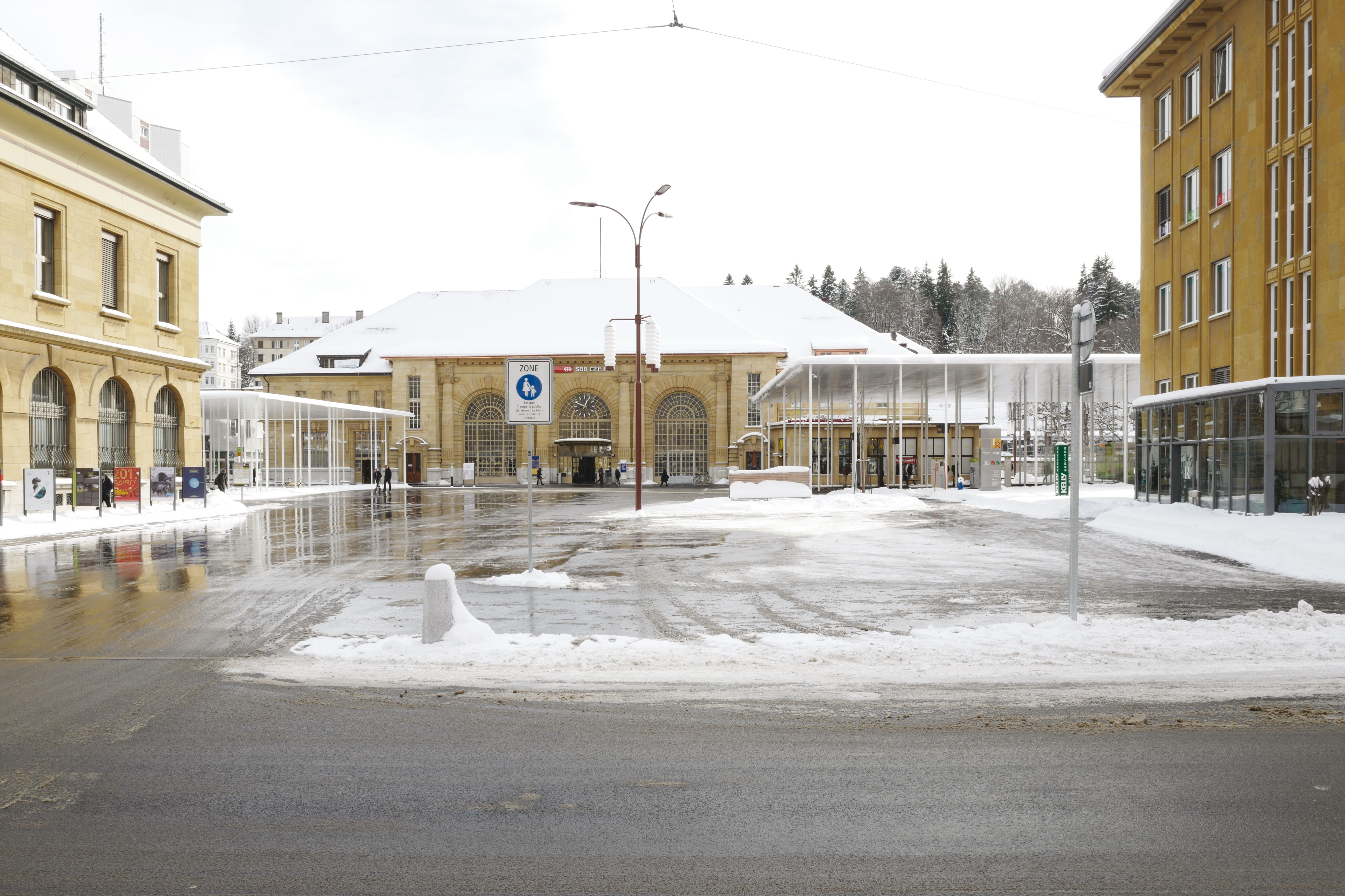 Le parvis de la gare vu depuis l’avenue Léopold-­Robert, cadré par les deux couverts. A droite, le bâtiment de l’ancienne Chambre suisse de l’horlogerie. A gauche, celui de la Poste.