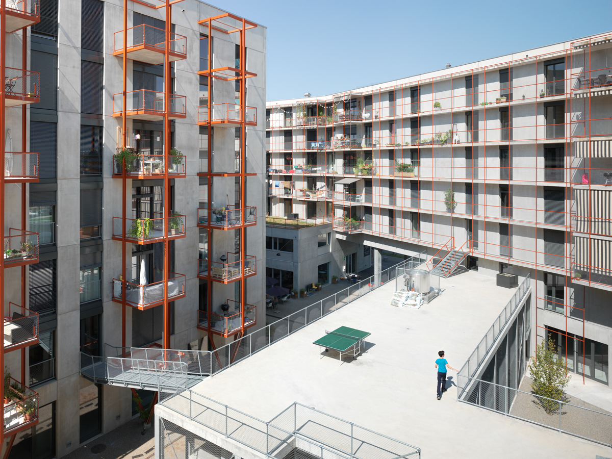 Die roten Stahlstrukturen der Balkone und Lauben­gänge werden in Zukunft mit Pflanzen bewachsen sein.