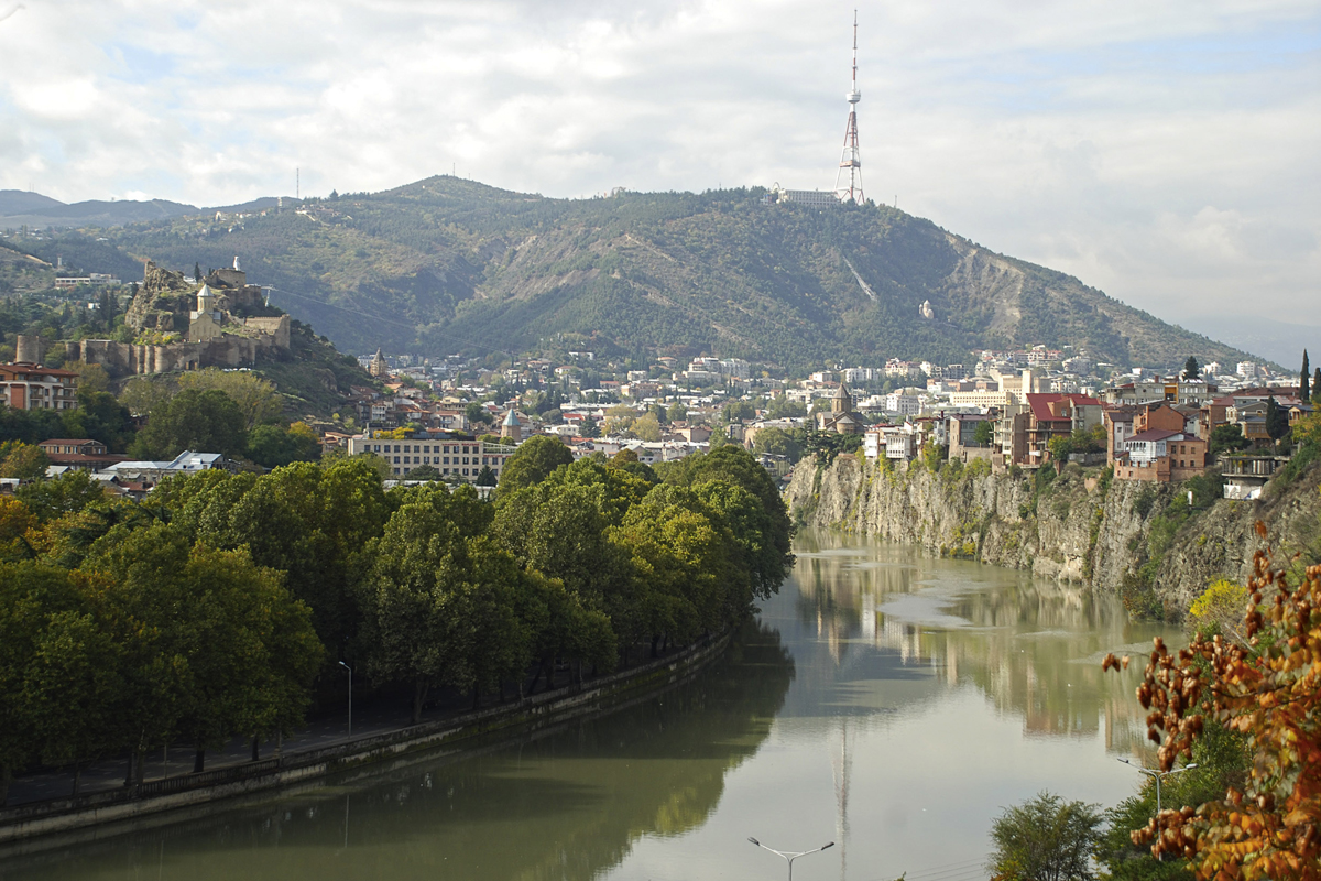 Tbilisi – der Blick nach Westen in die Mtkwari-Schlucht. Links die Burg Nariqala und ihr zu Füssen die Altstadt. Rechts die gewagt an den Rand gebauten Wohnhäuser im ehemals armenisch geprägten Quartier Avlabari.
