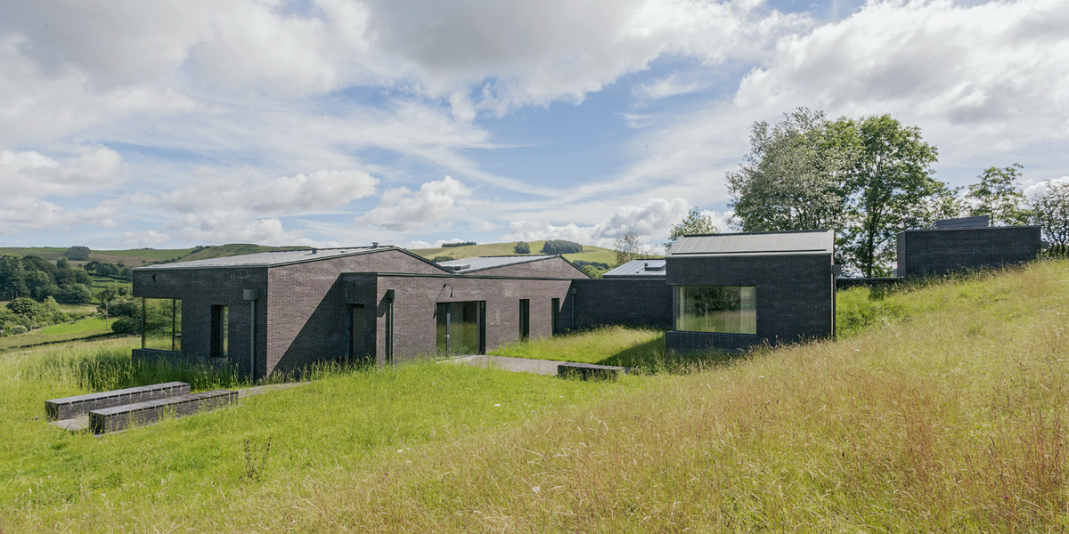 John Pawsons «Life House»: Die scharfkantigen Baukörper werden durch die Materialität des dunklen Ziegelsteins auf natürliche Art zum Teil der Landschaft.