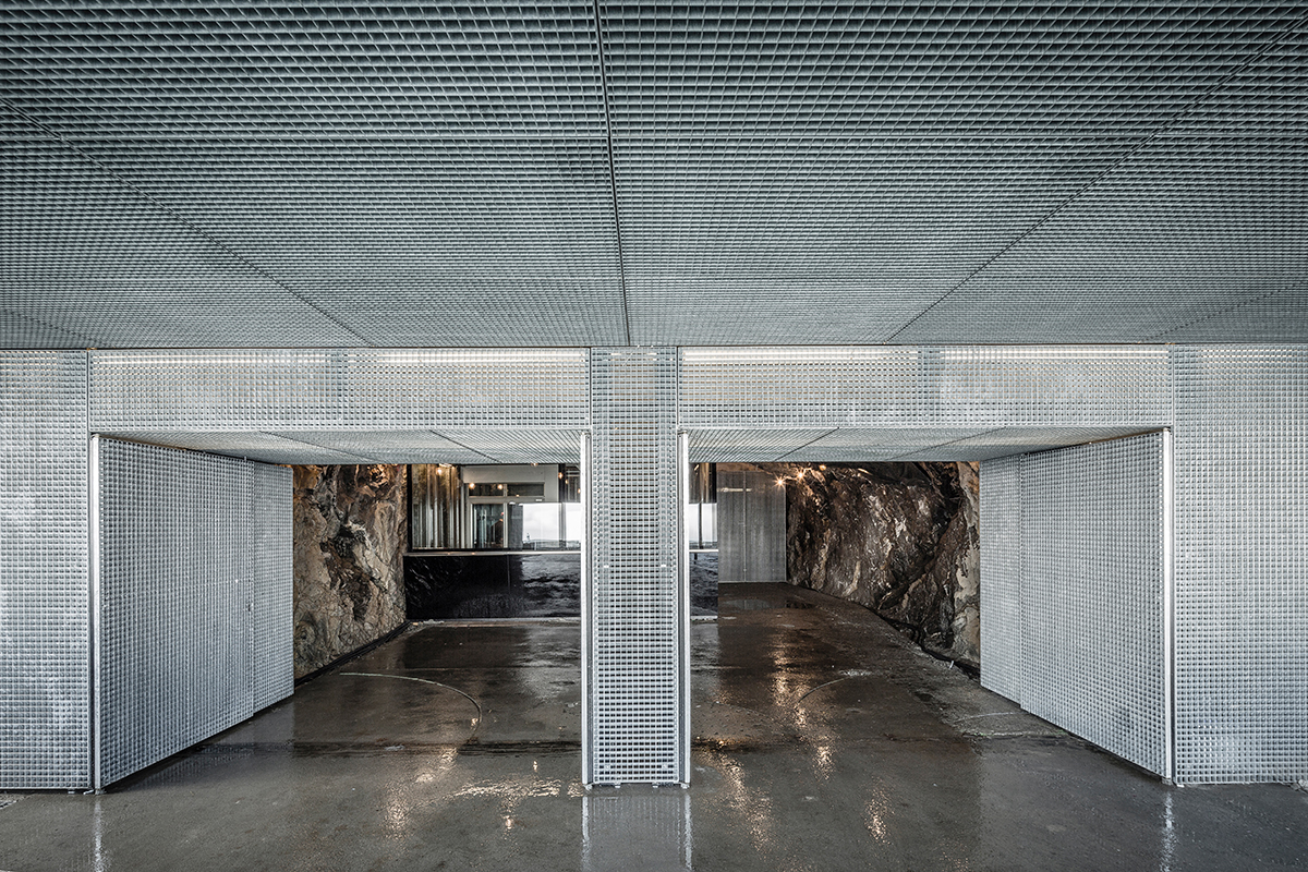 Der Zugangspavillon ist aus einer Metallgitterverkleidung konstruiert, die sich um den nackten Fels legt.